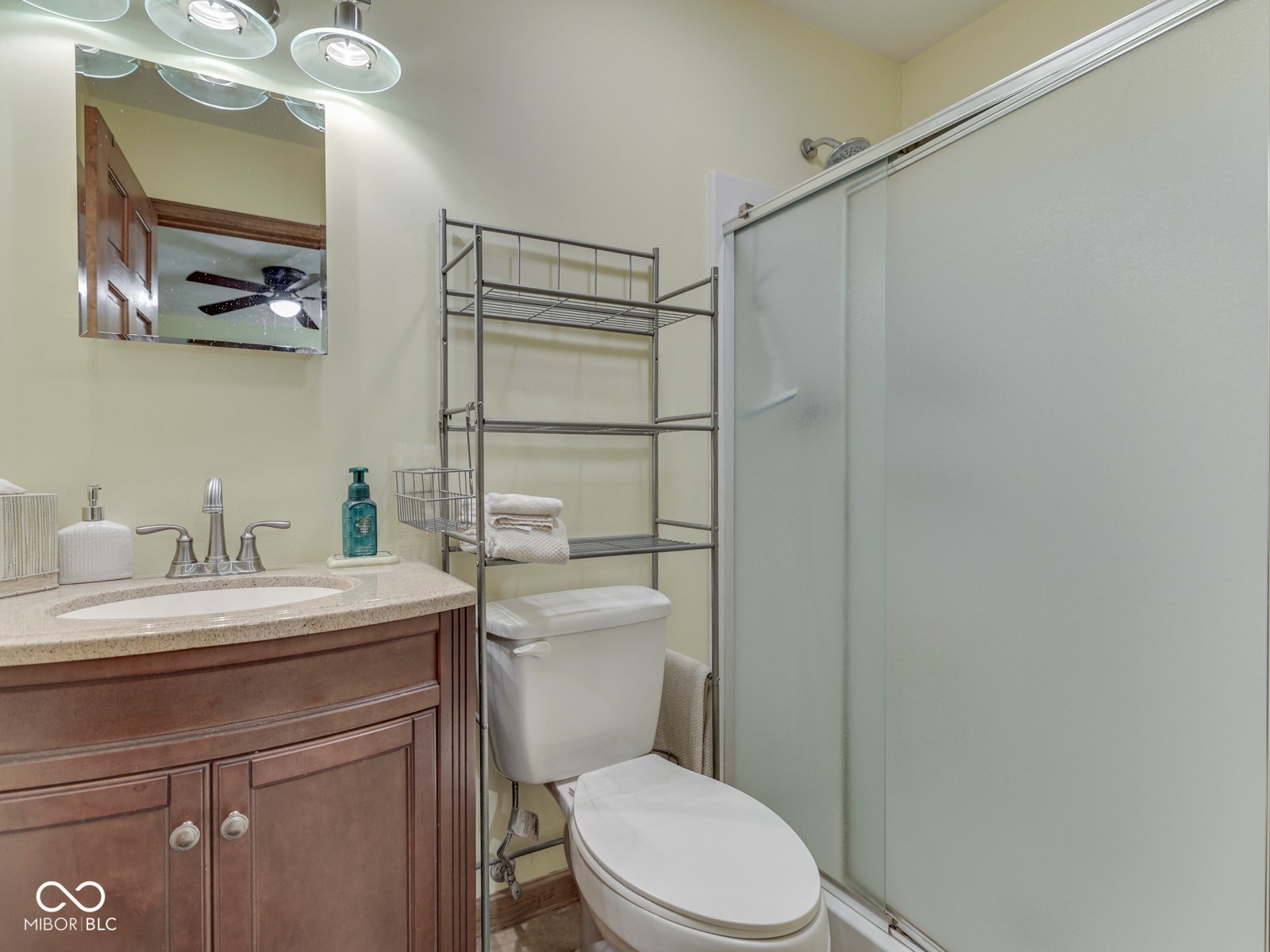 Vanity with a light-colored countertop and undermount sink, brushed nickel faucet, mirror, and overhead light fixture