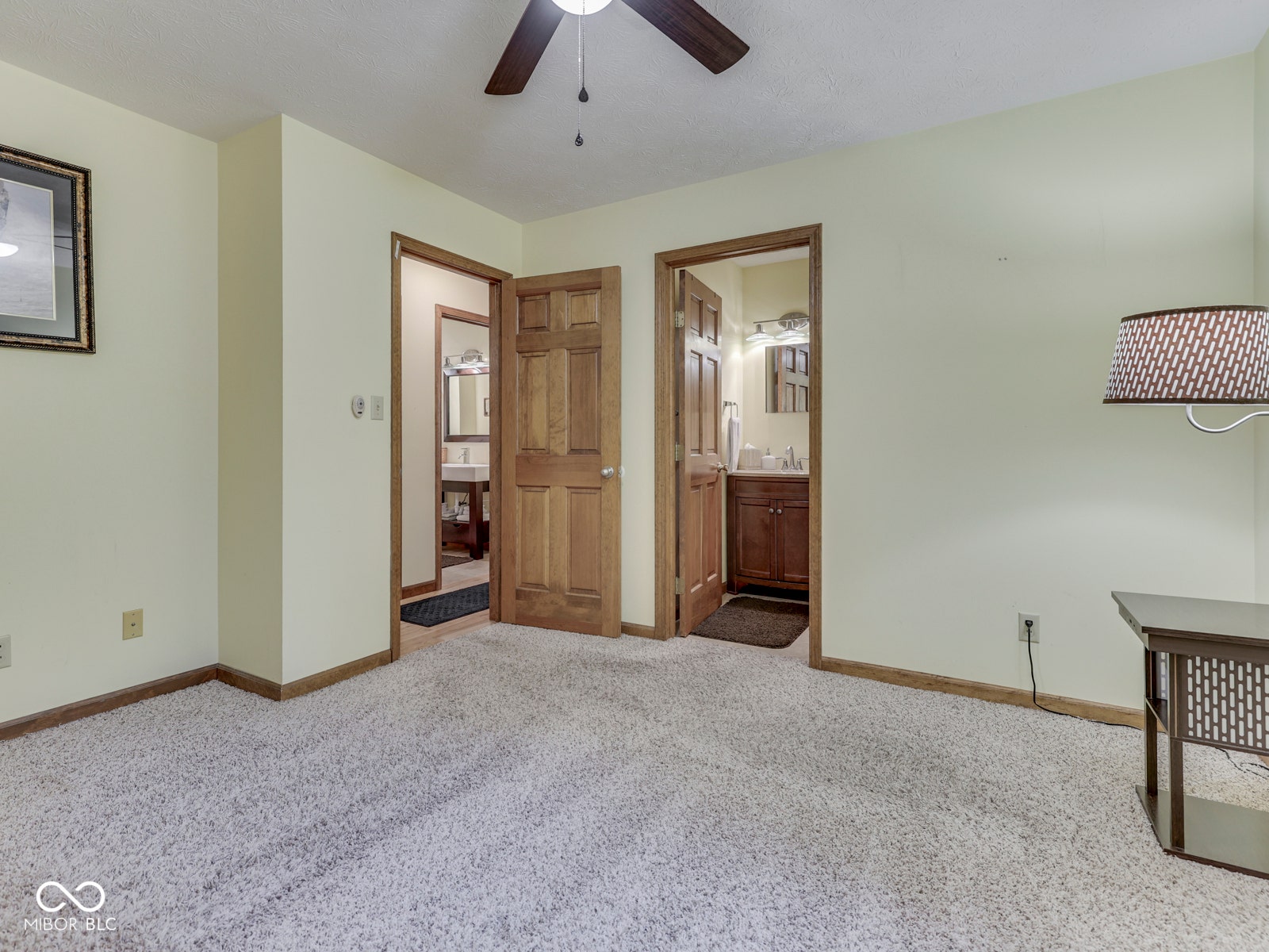 Plush carpet flooring, wood-paneled doors, and a ceiling fan with integrated lighting