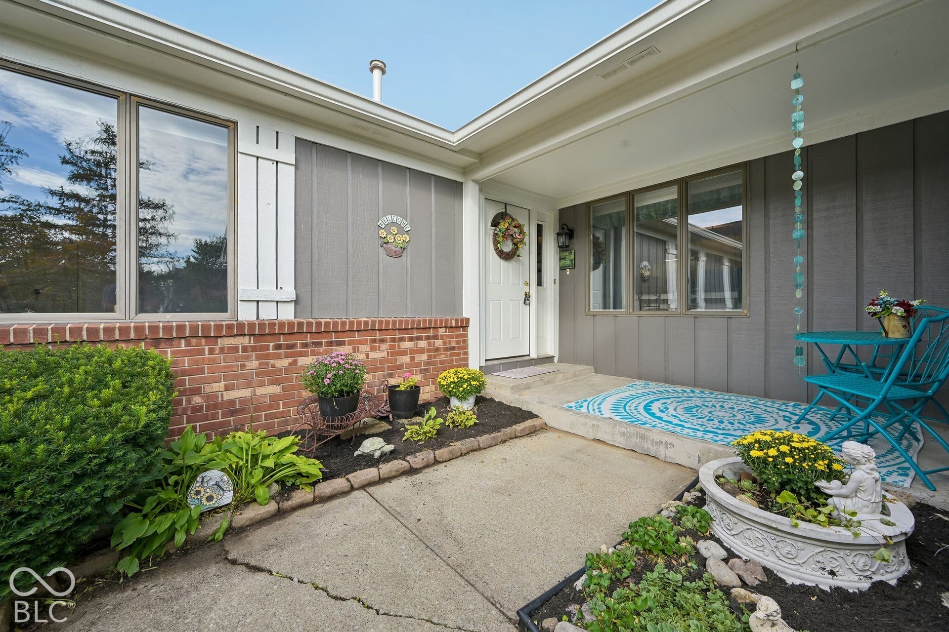 Brick facade with gray vertical siding, front entry with white door, and front landscaping