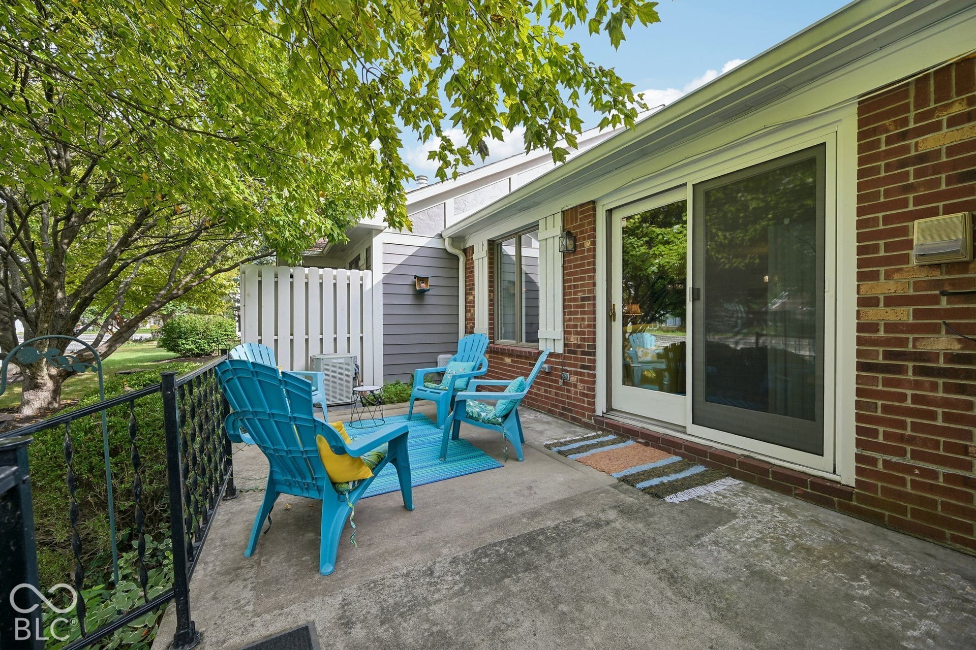 Concrete patio with brick exterior, sliding glass door, and white privacy fence
