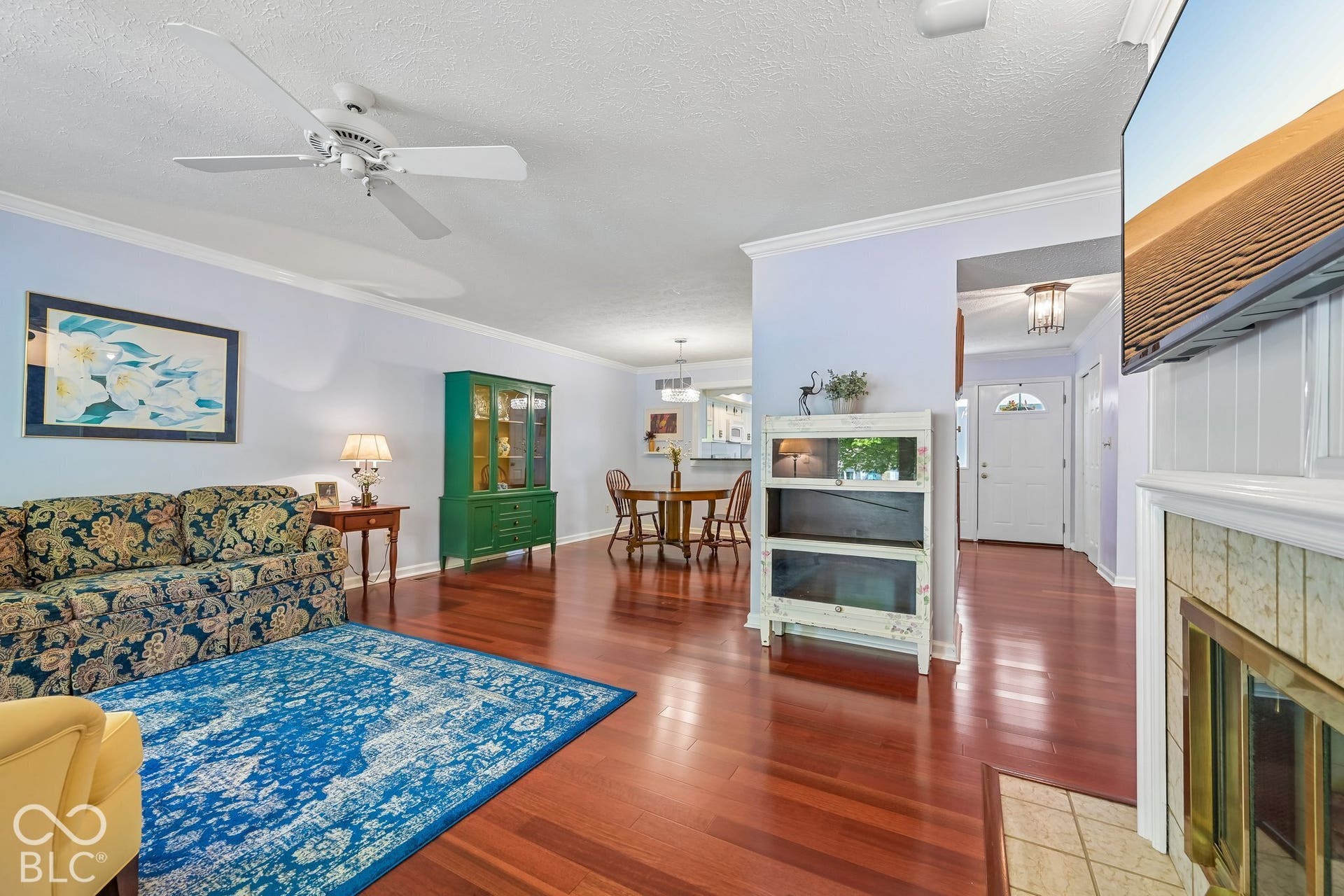 Wood-finish flooring throughout, crown molding detailing, and a fireplace with a tiled hearth