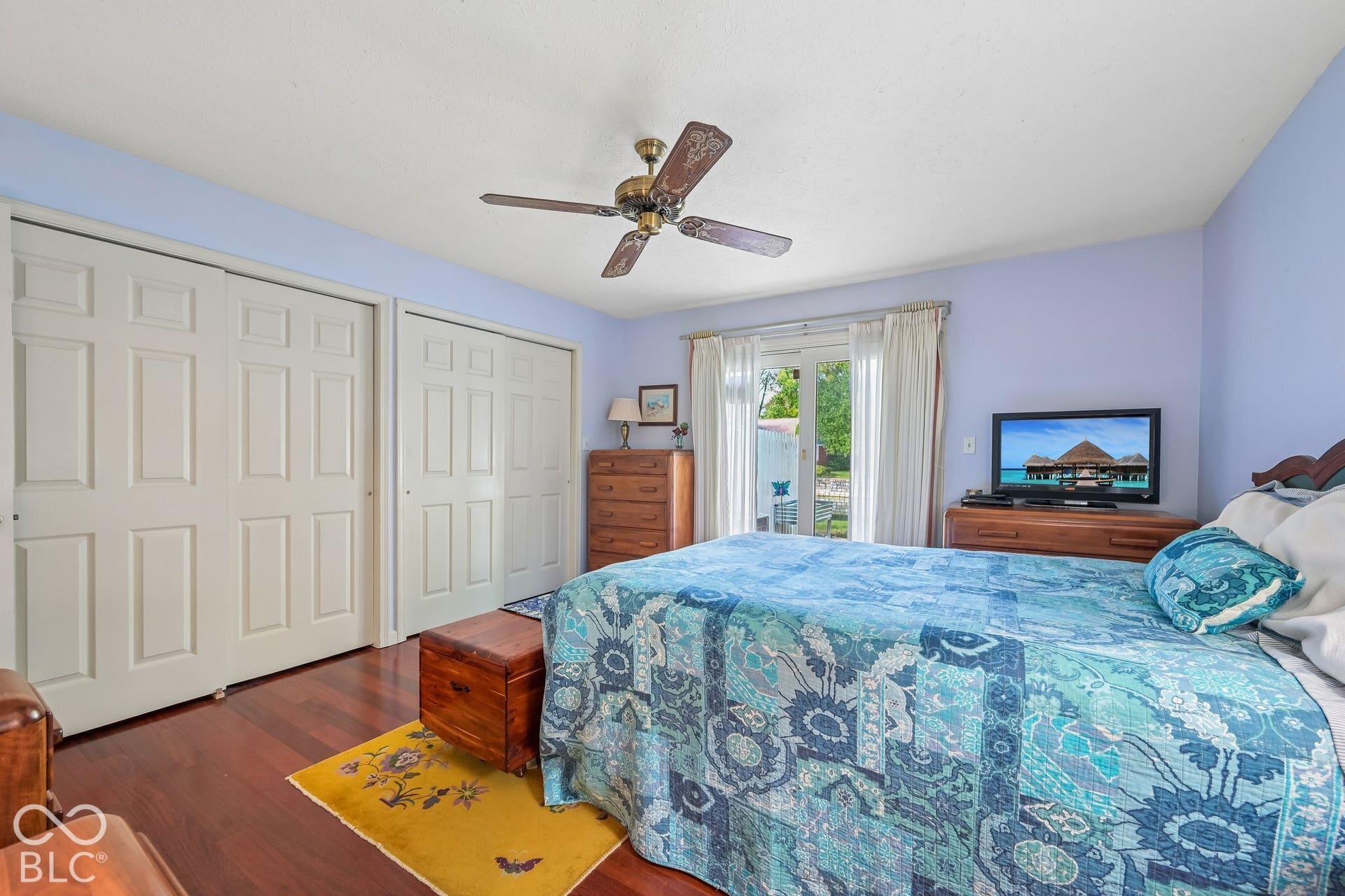 Wood-finish flooring, dual panel closet doors, ceiling fan with integrated lighting, and sliding glass doors to the exterior