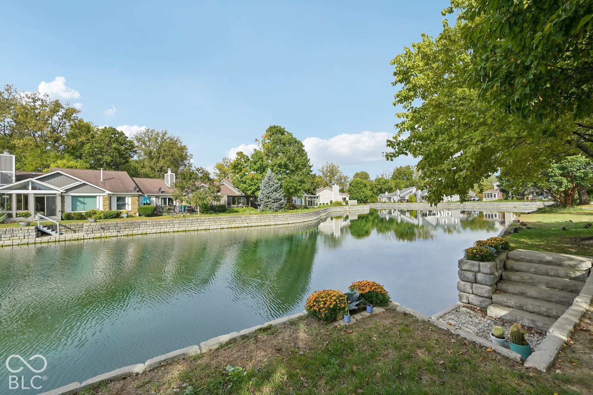 Waterfront property with a stone retaining wall, concrete steps, and established landscaping