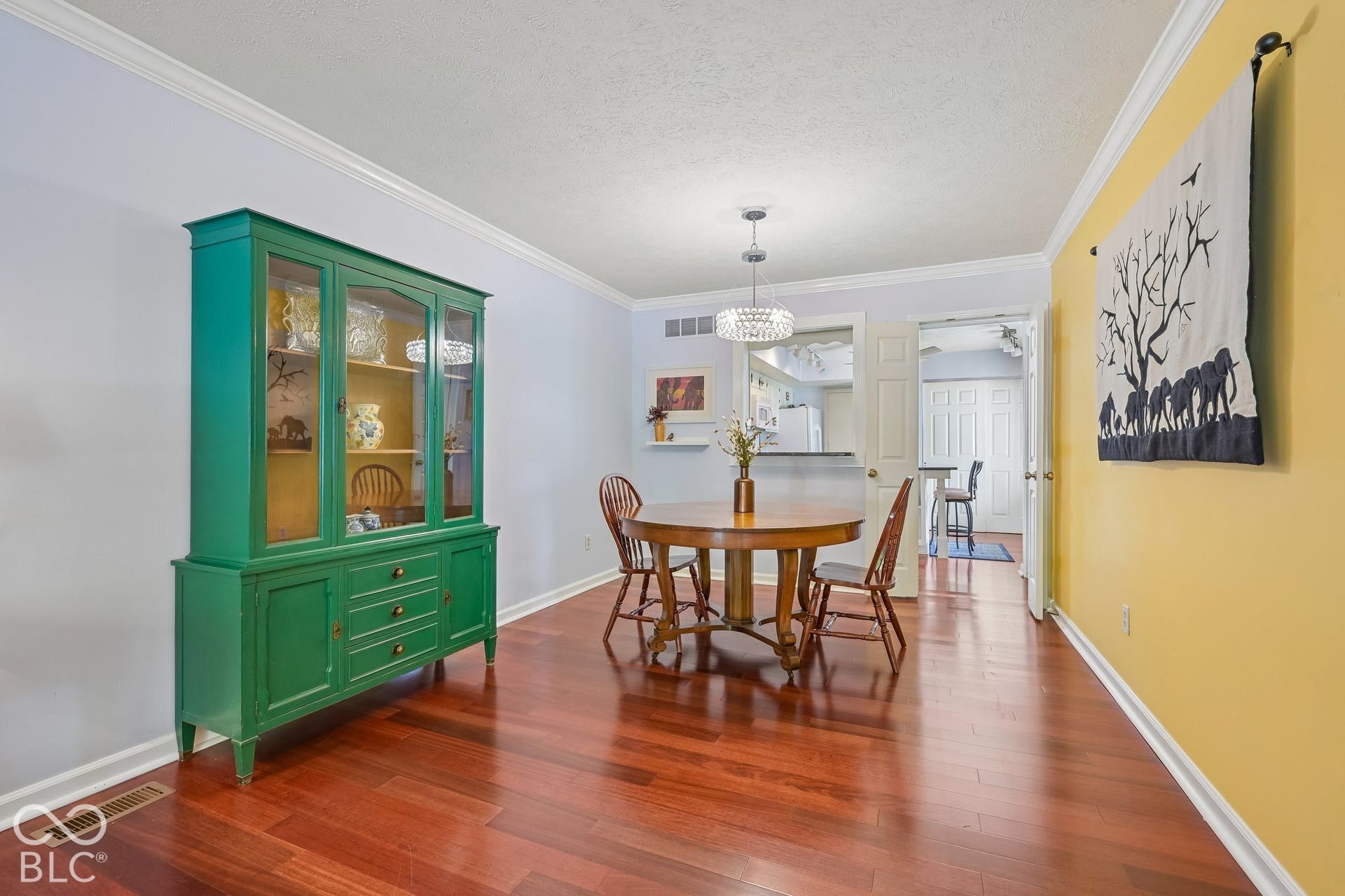 Wood-finish flooring throughout, crown molding, and a contemporary chandelier