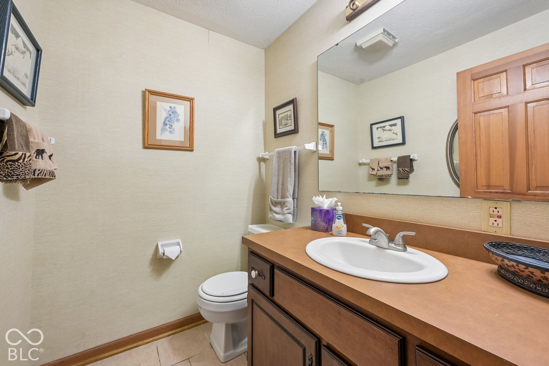 1/2 Bathroom (Basement) featuring a wood-finish vanity with an integrated sink, a large wall-mounted mirror, and tile flooring