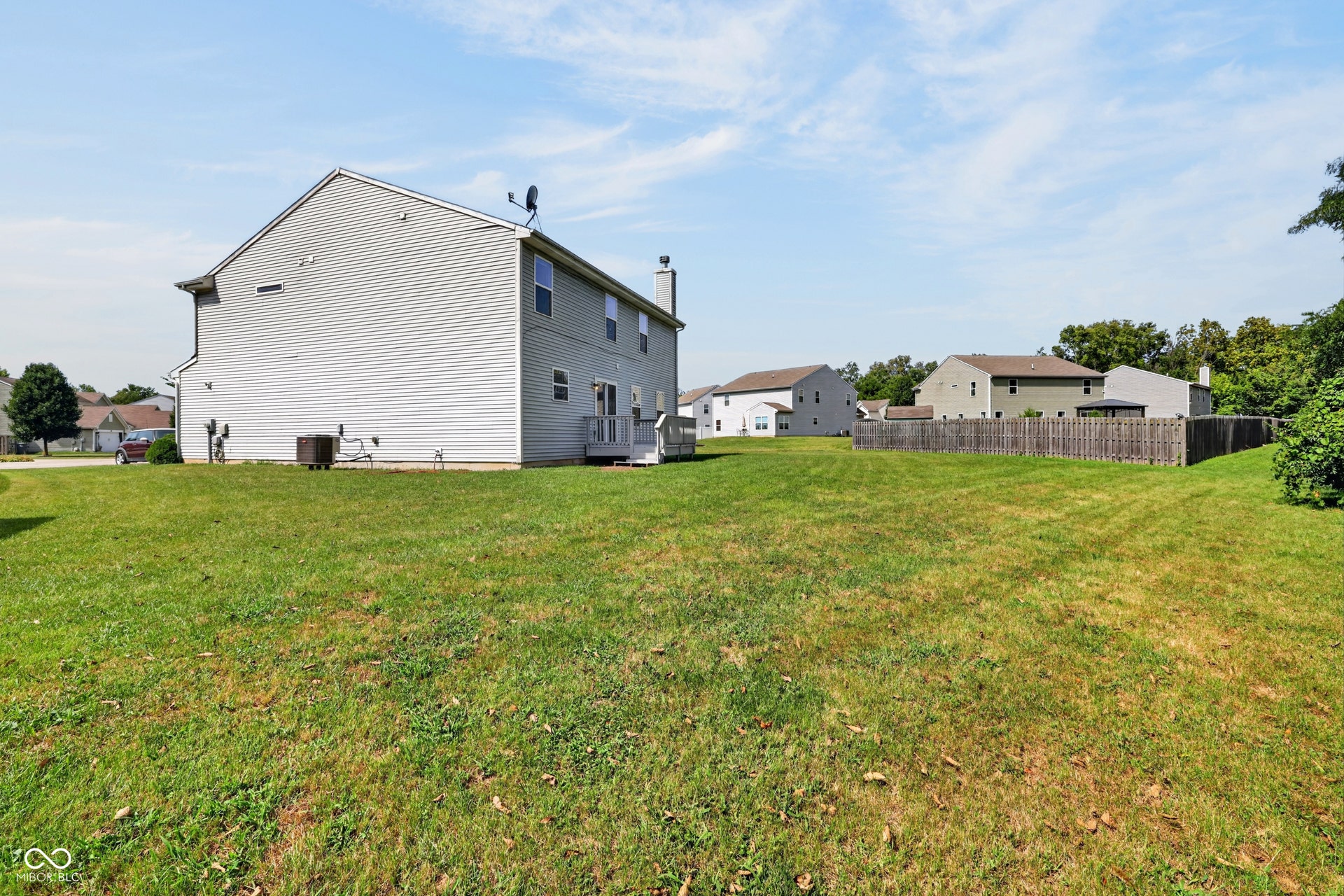 Expansive grassy yard with a multi-level exterior and a rear deck