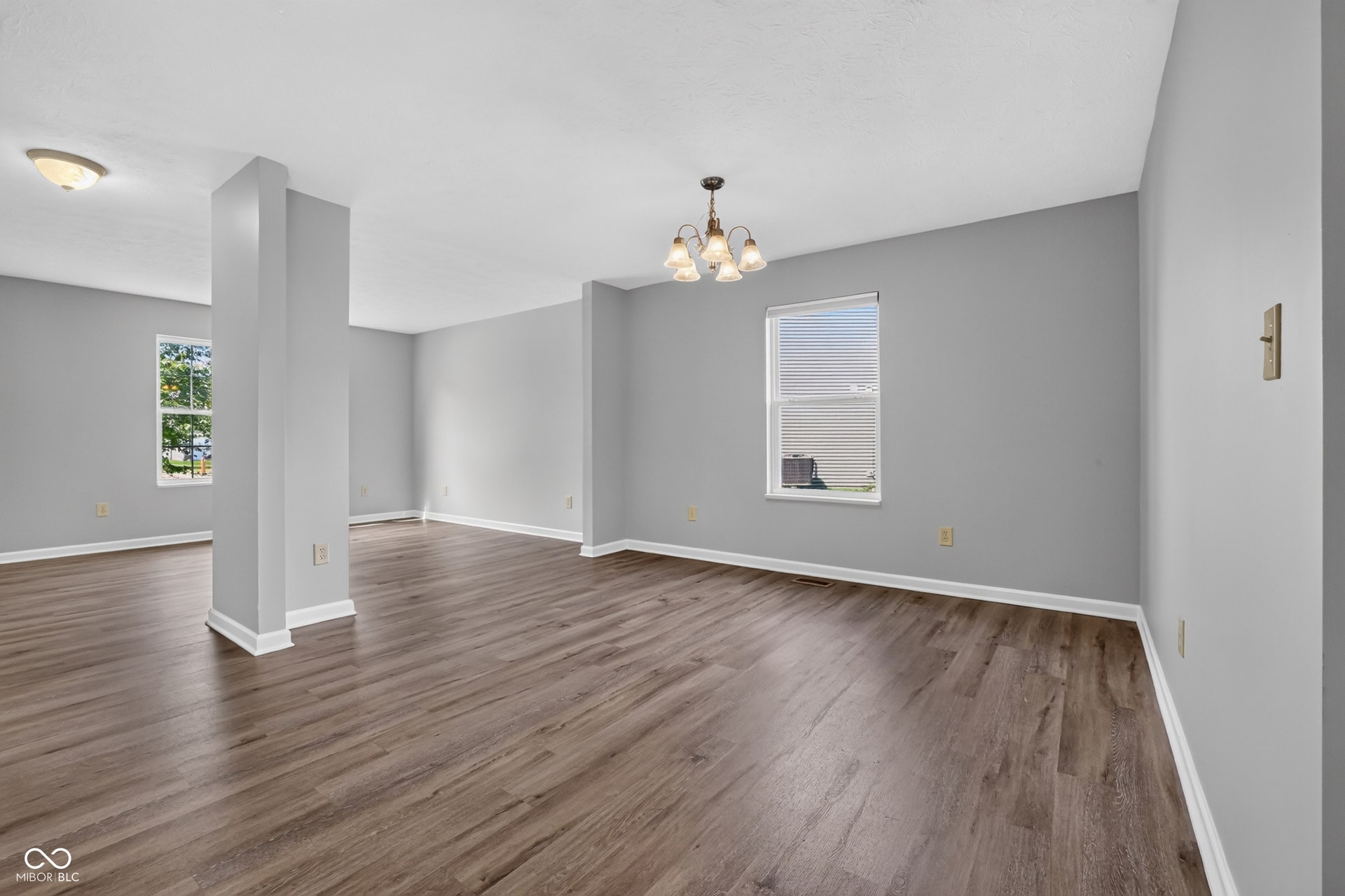 Wood-finish flooring throughout, complemented by a contemporary light fixture, recessed lighting, and bright white trim
