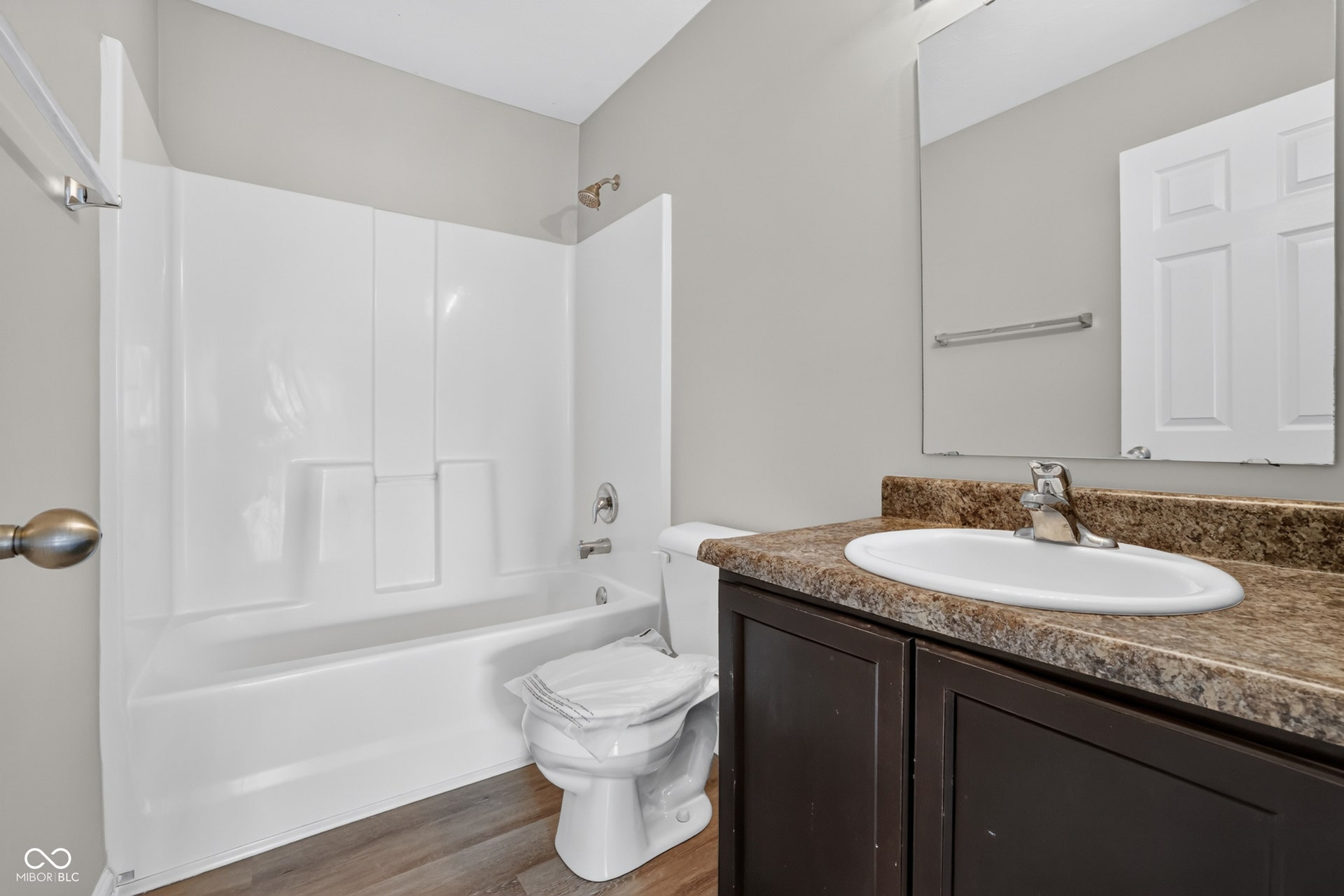 Wood-finish flooring with a vanity featuring a brown countertop and integrated sink