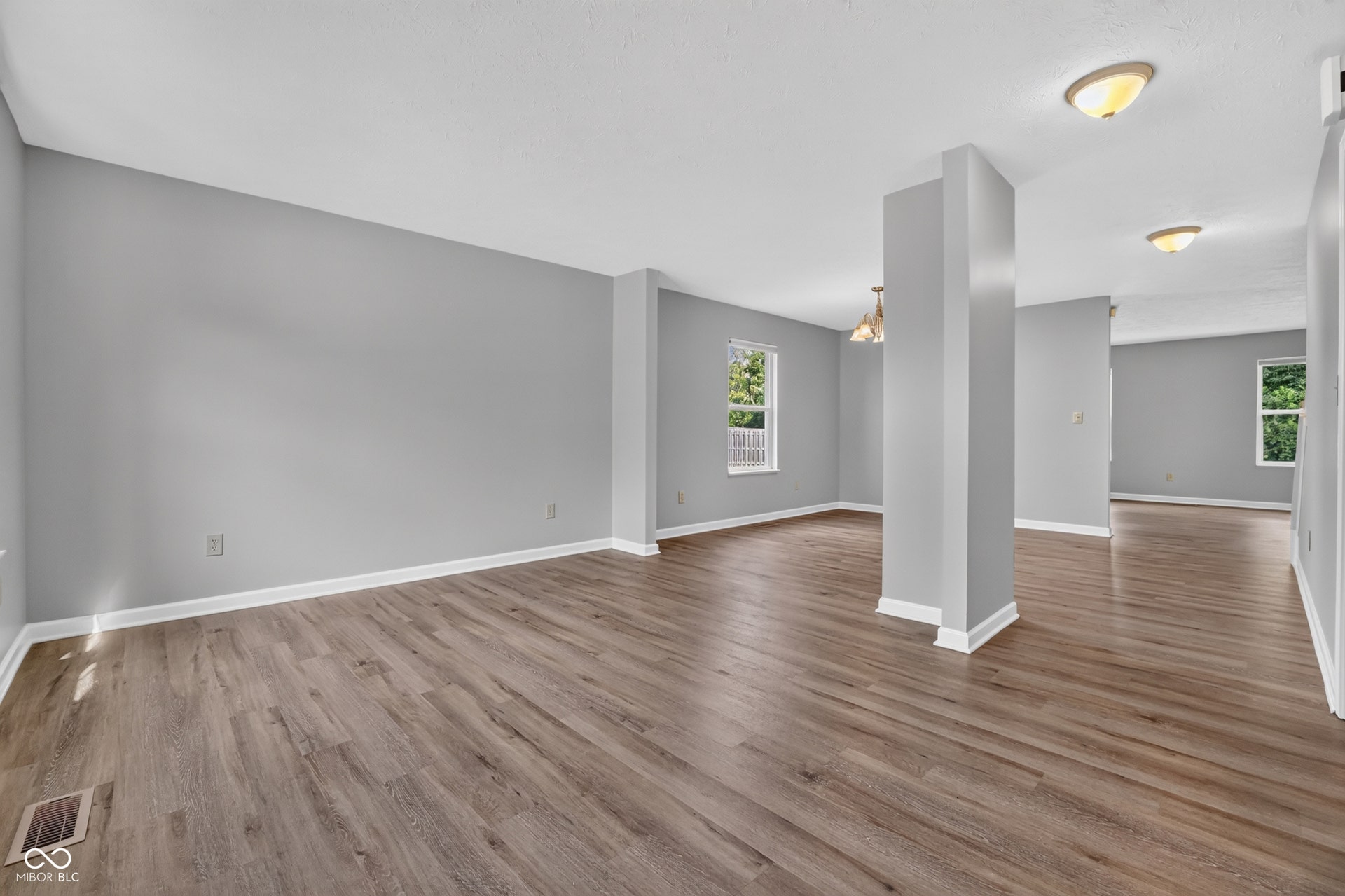 Expansive open-concept room featuring wood-finish flooring, neutral gray walls, white trim, and recessed lighting