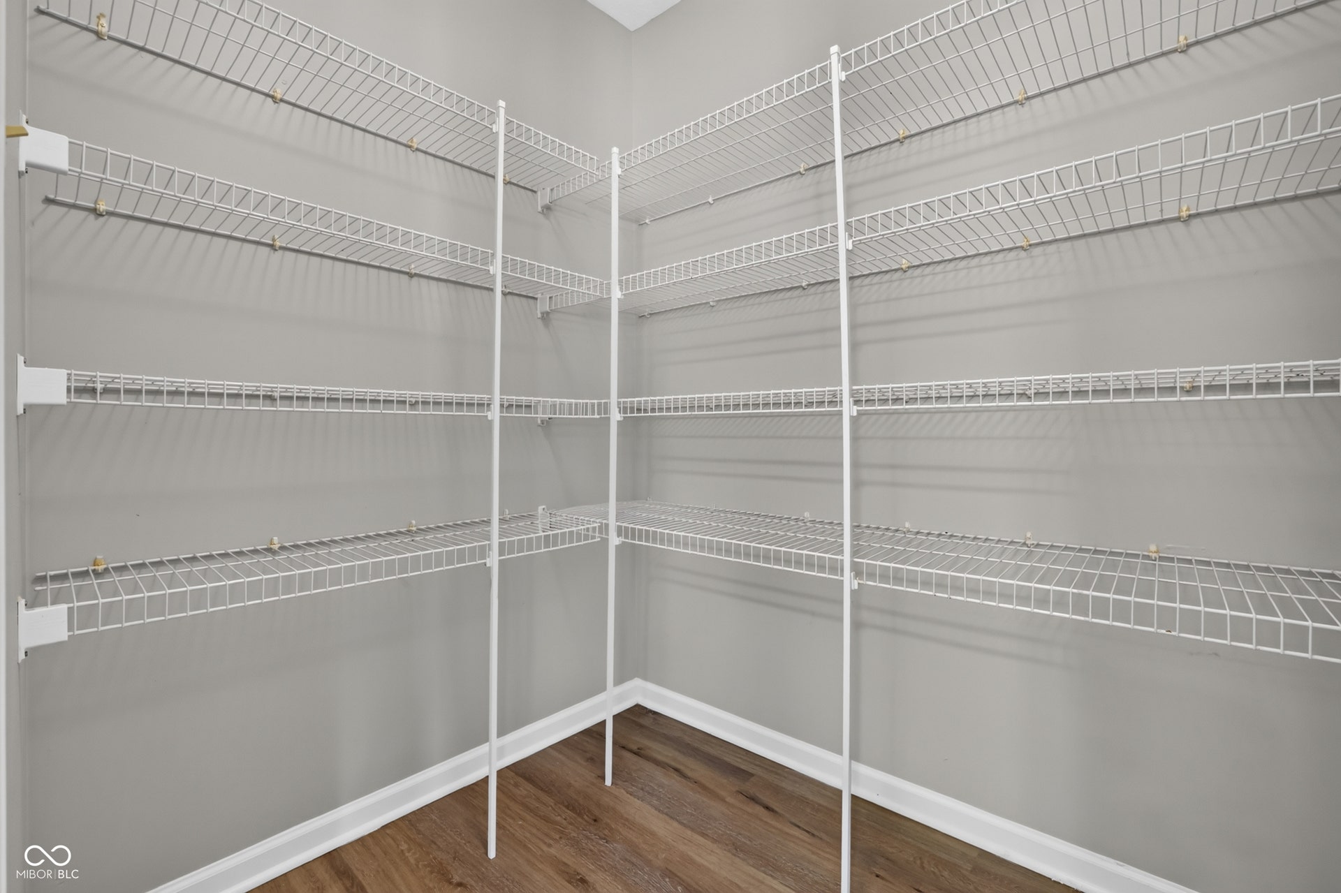 Built-in wire shelving system, light gray wall paint, and wood-finish flooring
