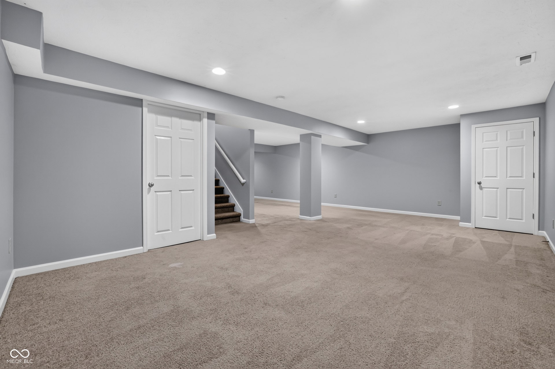 Spacious room with plush carpeting, recessed lighting, and a neutral wall color