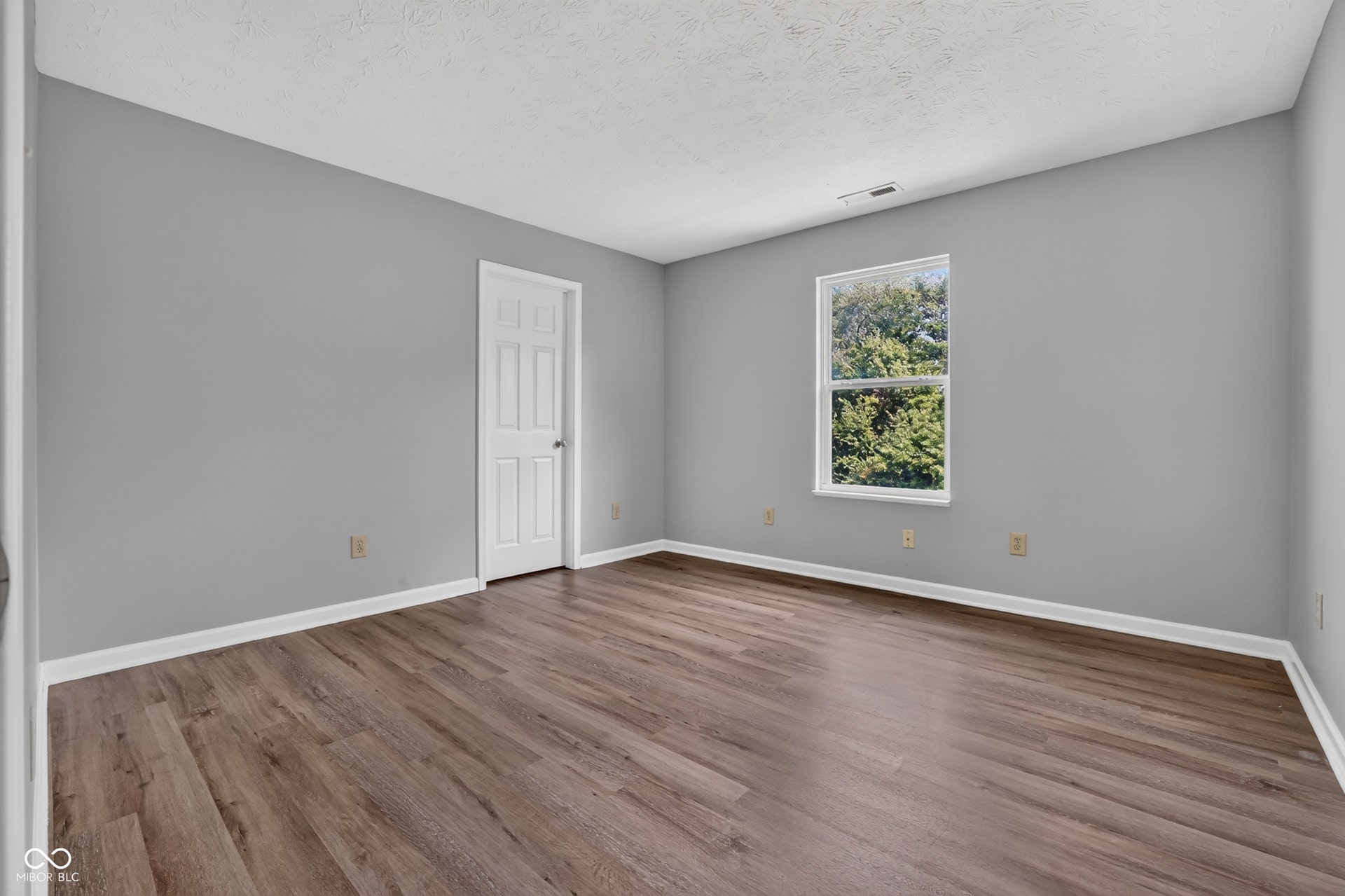 Wood-finish flooring with white trim, light gray painted walls, and a single window
