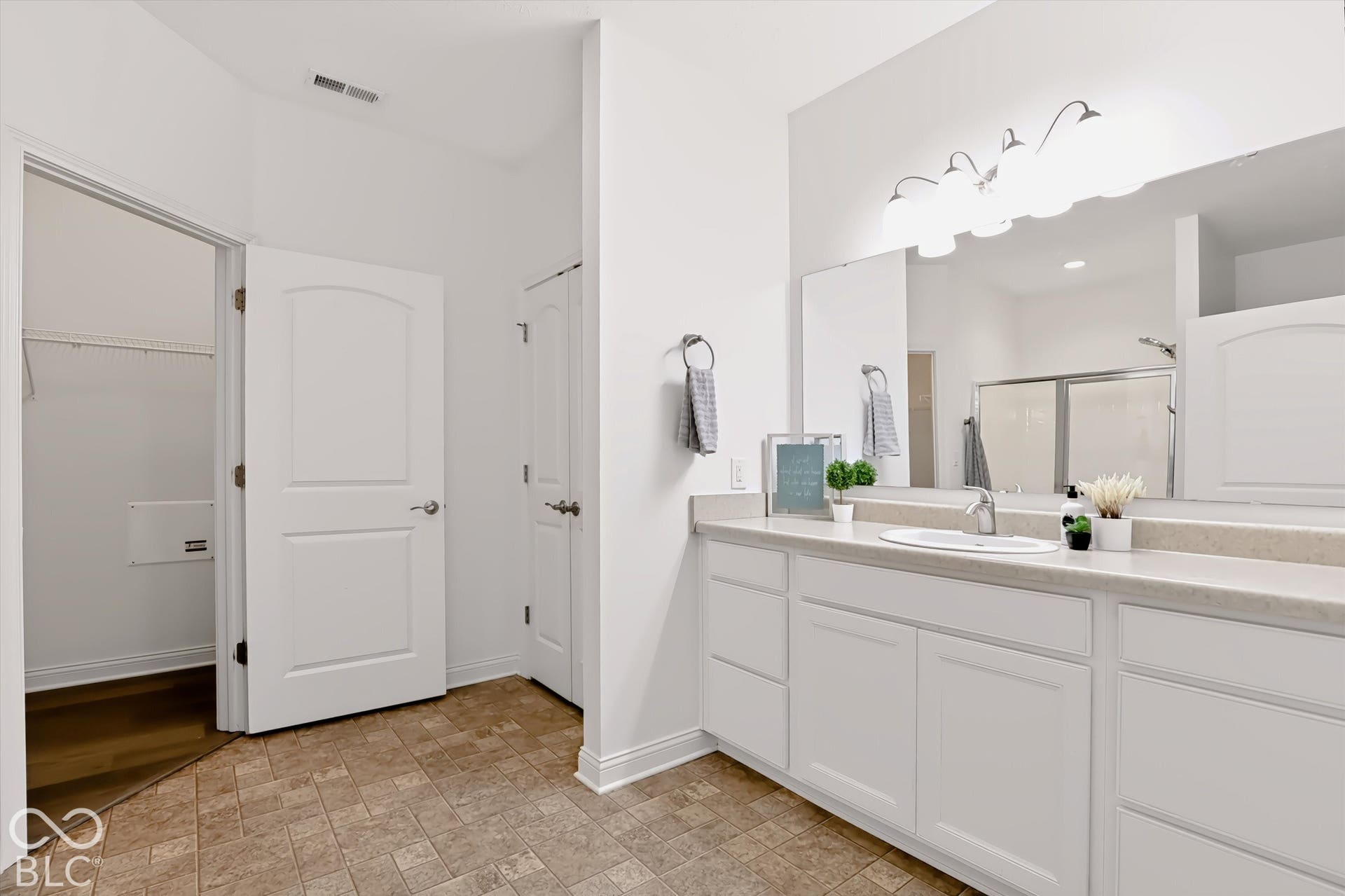 6520 Coughlan Drive, Indianapolis, IN 46278 Dual sink vanity with light-toned countertop, extensive wall-mounted mirror, and overhead lighting