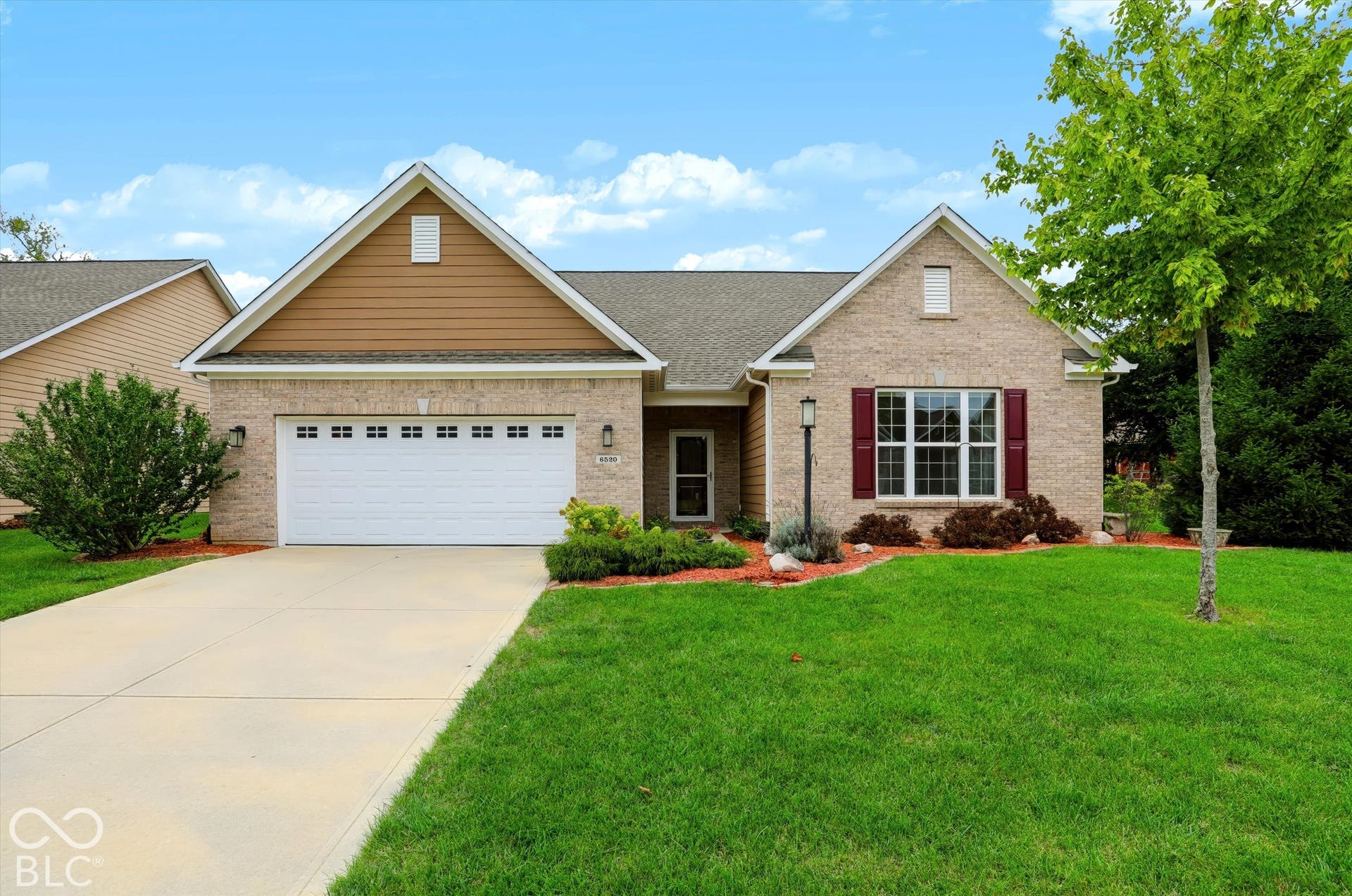 6520 Coughlan Drive, Indianapolis, IN 46278 Brick facade with accent siding, attached two-car garage, concrete driveway, front lawn, and mature landscaping