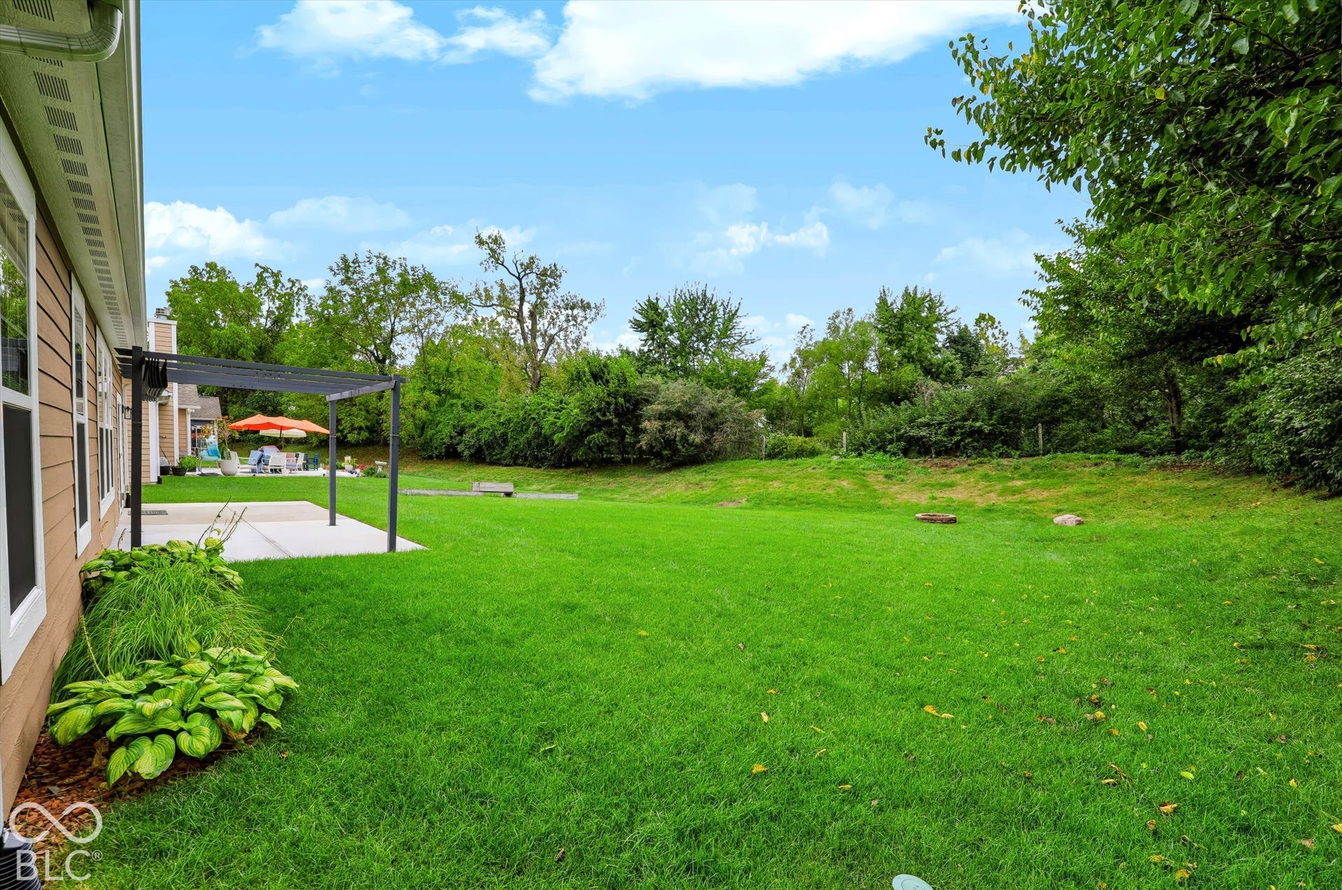 6520 Coughlan Drive, Indianapolis, IN 46278 Expansive green lawn with established trees, concrete patio, and a pergola structure