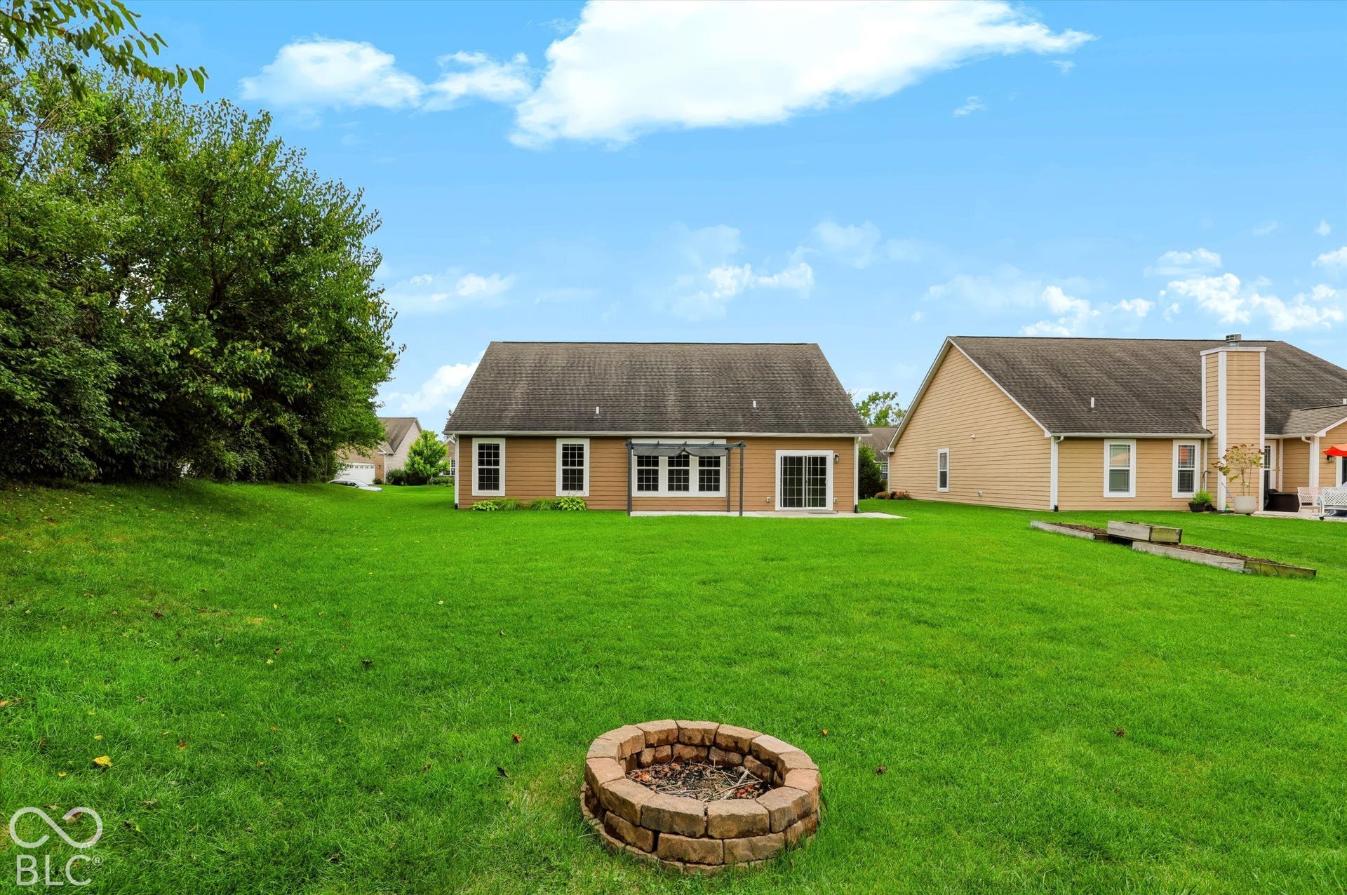 6520 Coughlan Drive, Indianapolis, IN 46278 Expansive green lawn with a built-in stone fire pit