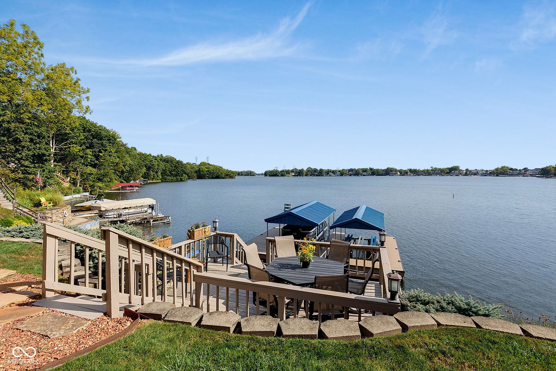 Waterfront property featuring an expansive wood deck, a custom boat dock with two covered slips.