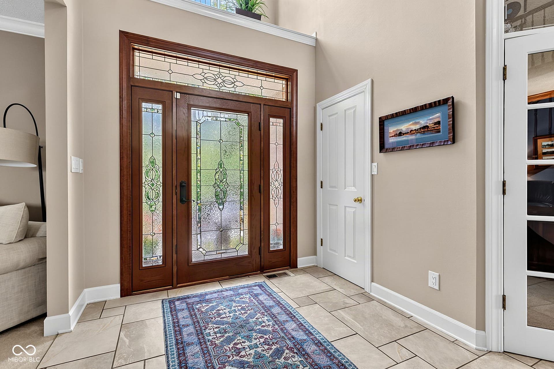Foyer with wood-finish entry door with decorative glass, transom window, and sidelights.