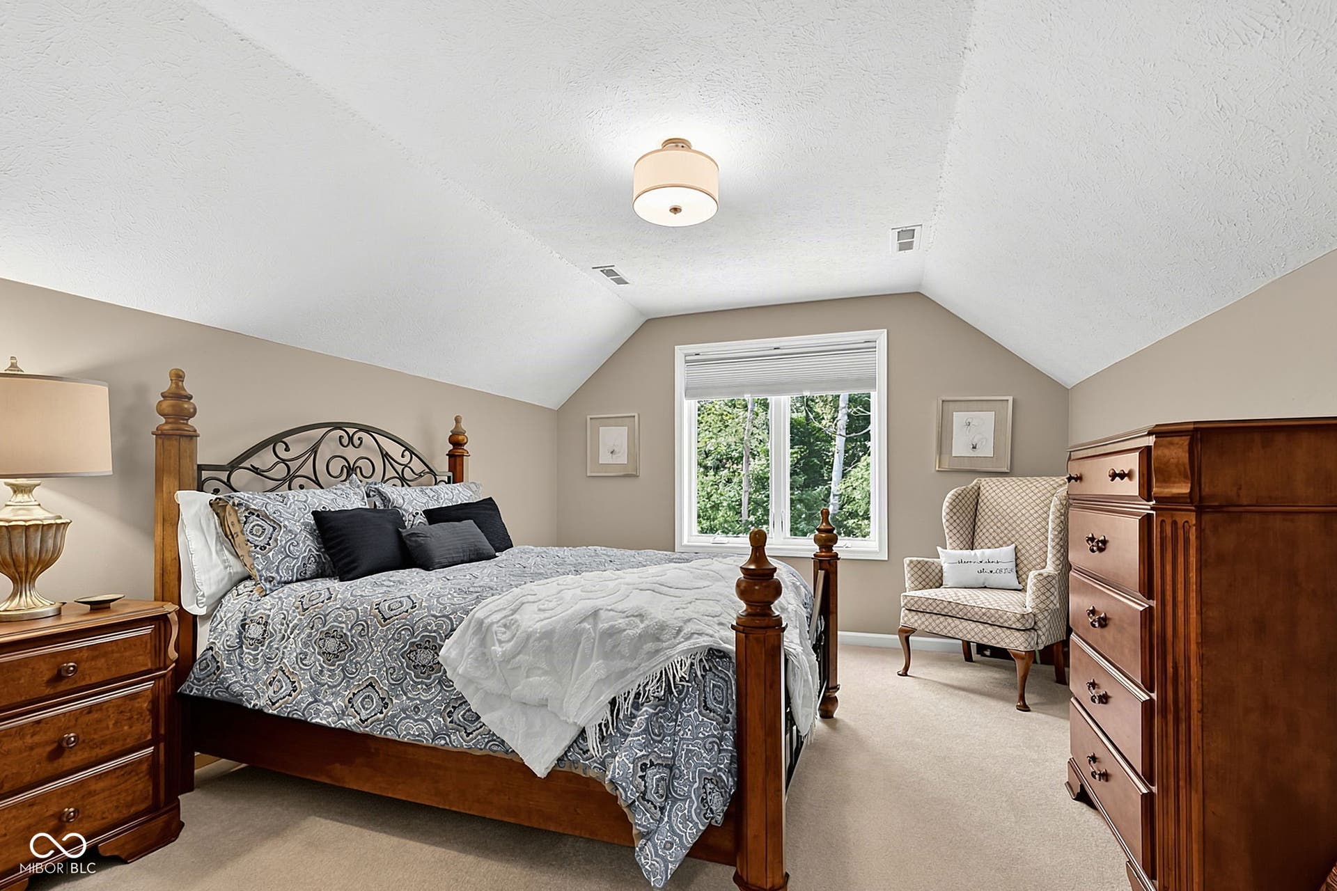 Vaulted ceiling with an overhead light fixture, neutral wall color, and a window with natural light