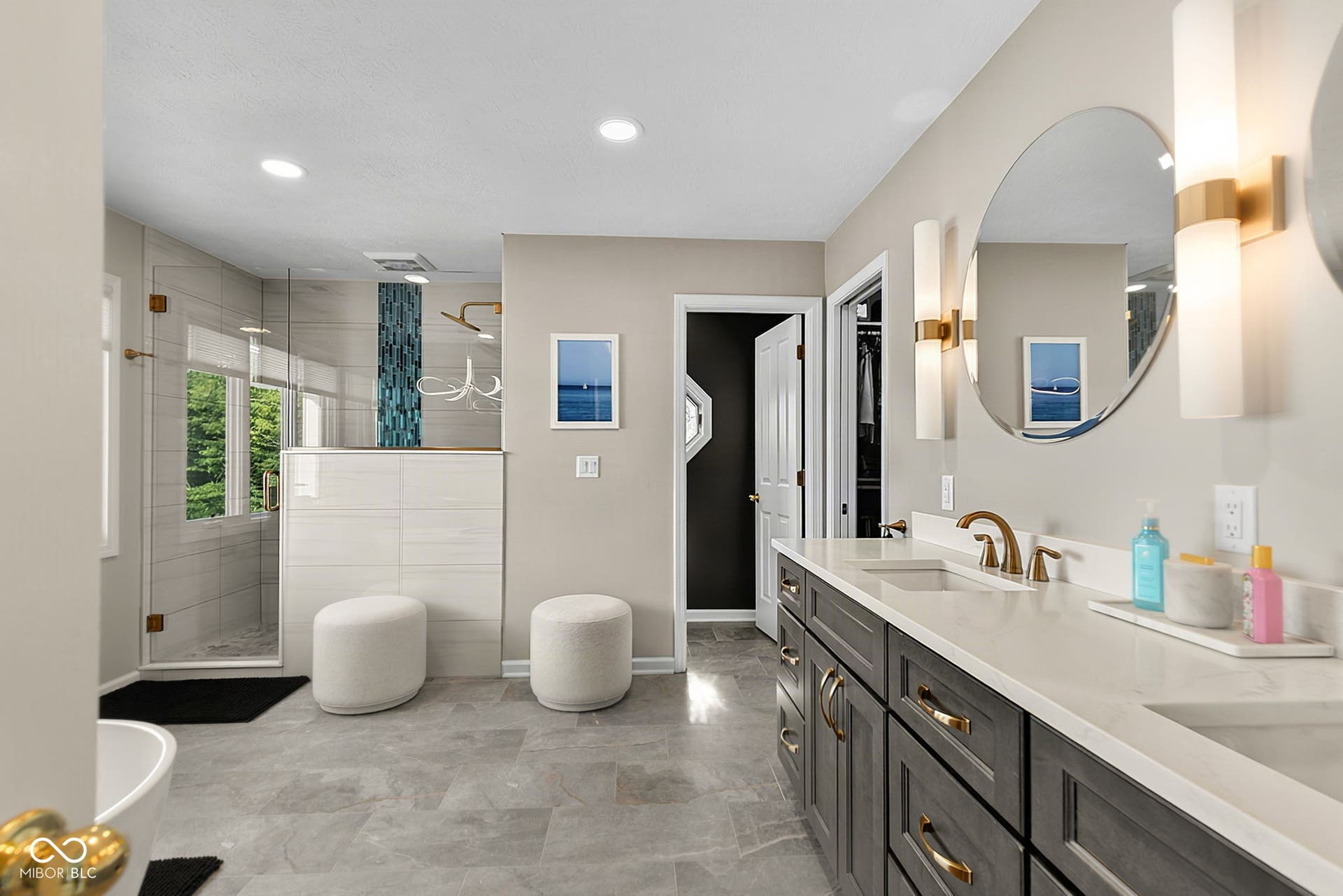 Primary ensuite with dual vanity with light-toned quartz countertops and matte gold fixtures.