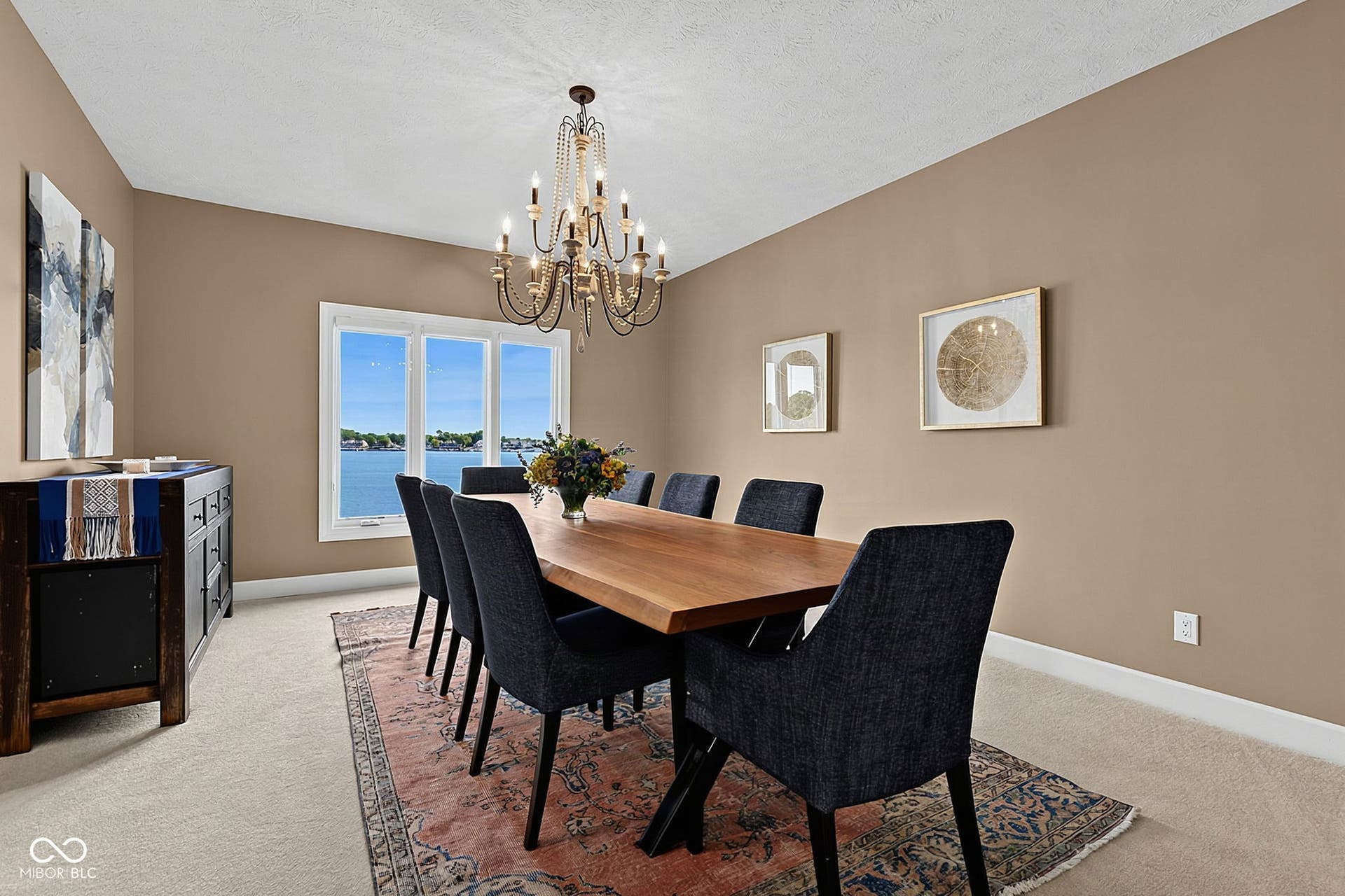 Large dining room with triple window with lake views near kitchen and living room.