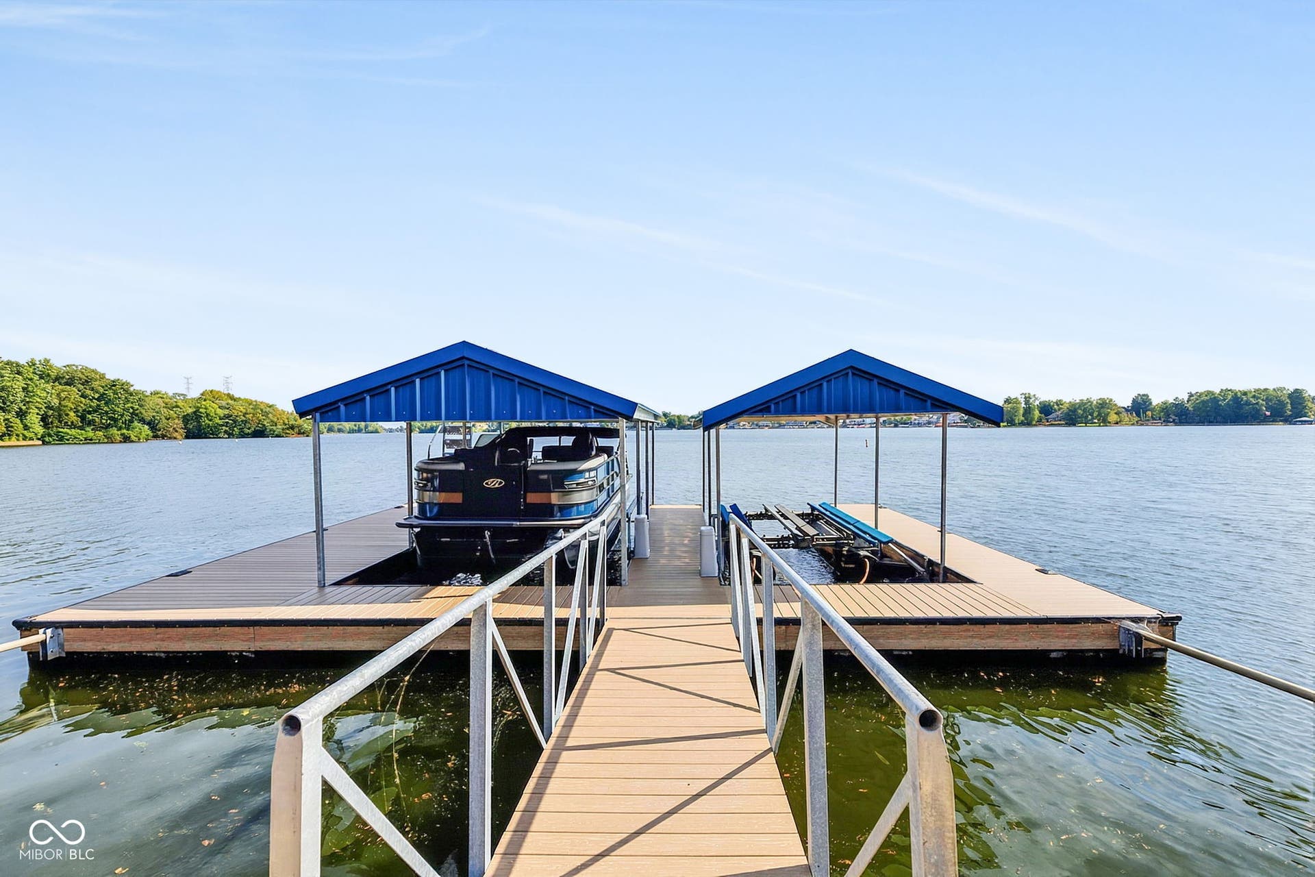 Oversized dock with two covered boat slips, wood-finish decking - heat resistant, and aluminum railings.