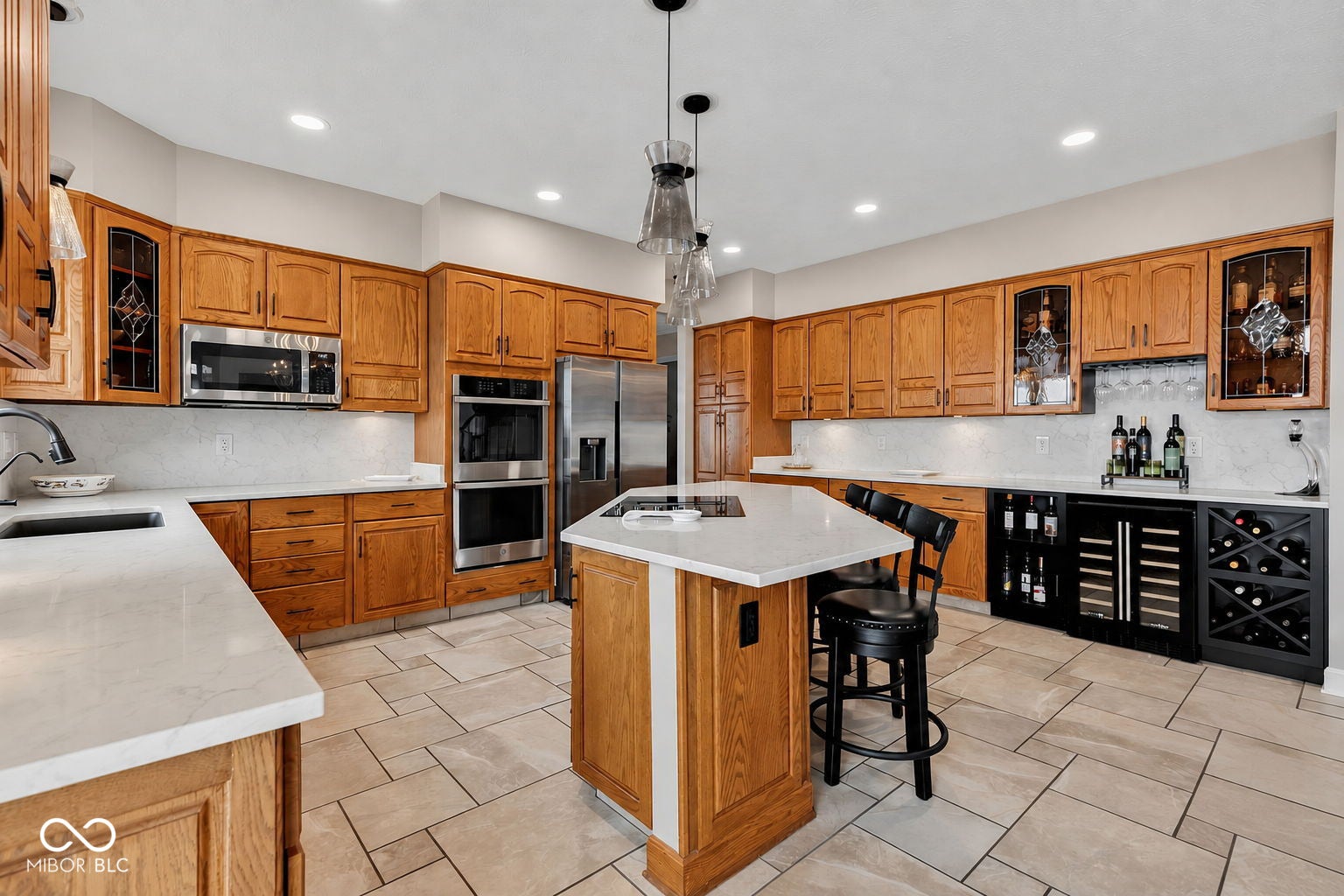 Well-appointed kitchen featuring light wood cabinetry, quartz countertops, and vatican tile flooring.