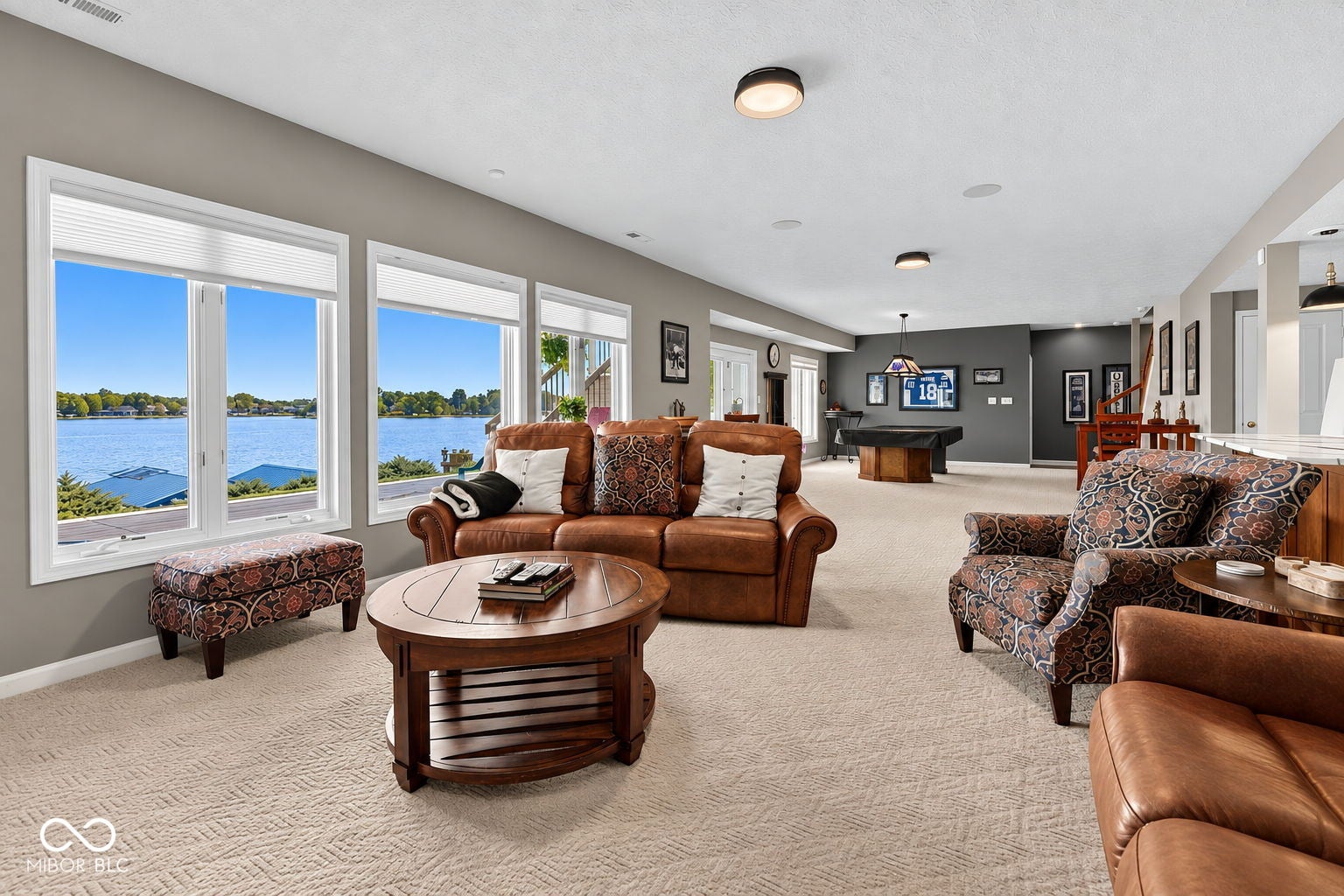 Expansive living space featuring multiple windows with water scenery, recessed lighting, and carpet flooring.