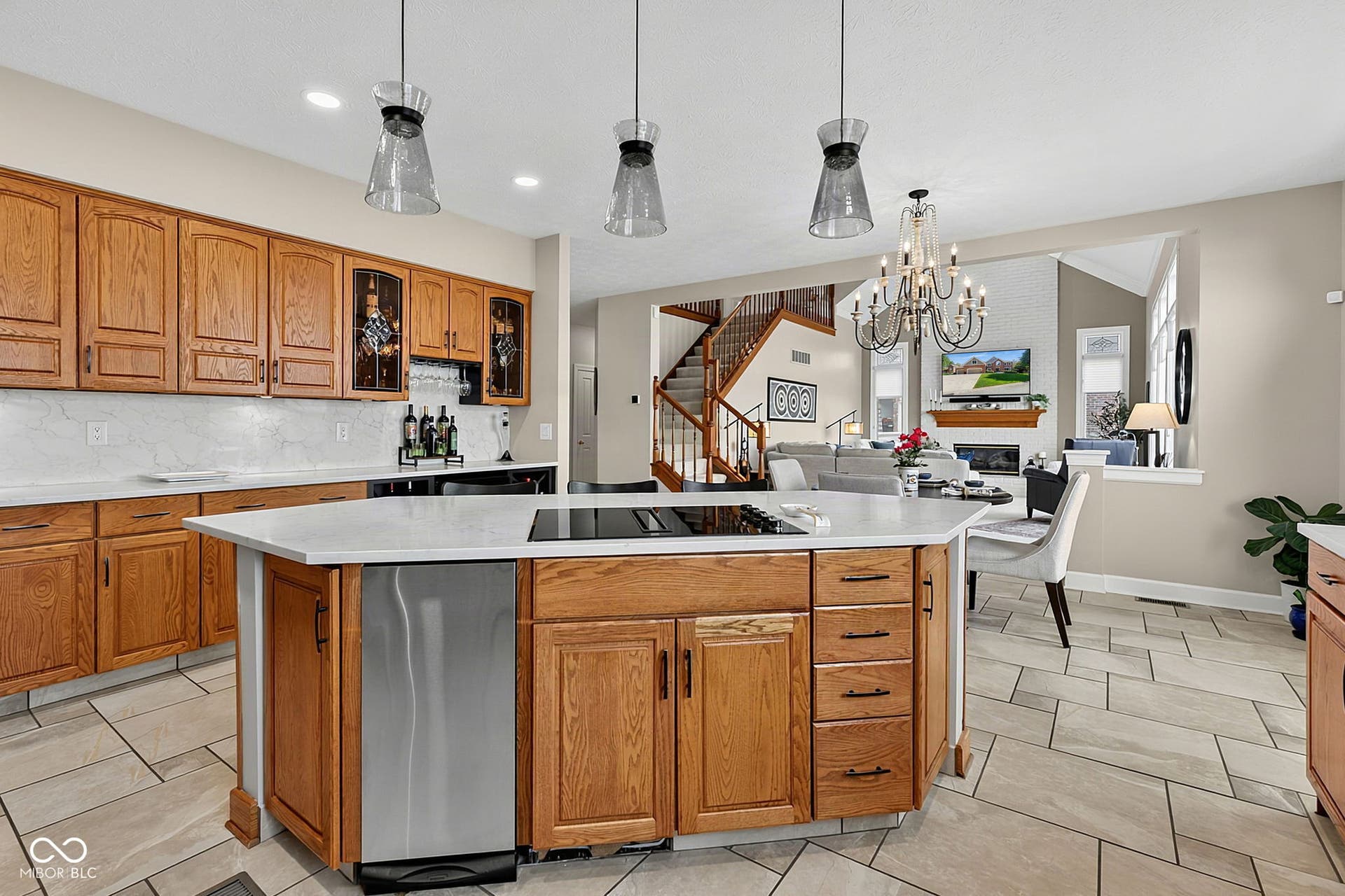 Kitchen featuring an island with integrated cooktop, stainless steel dishwasher, and pendant lighting.