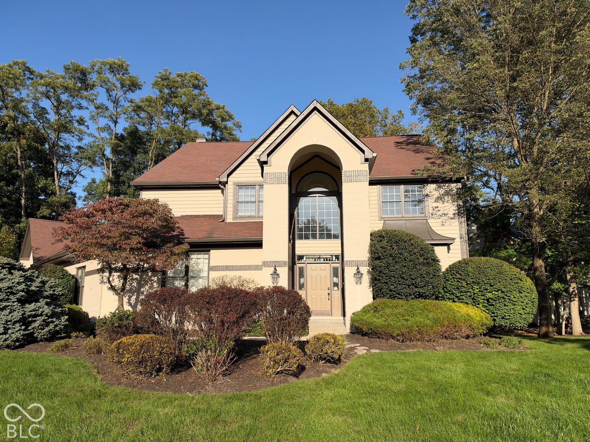 Two-story facade with arched entry, expansive windows, and a multi-level roofline