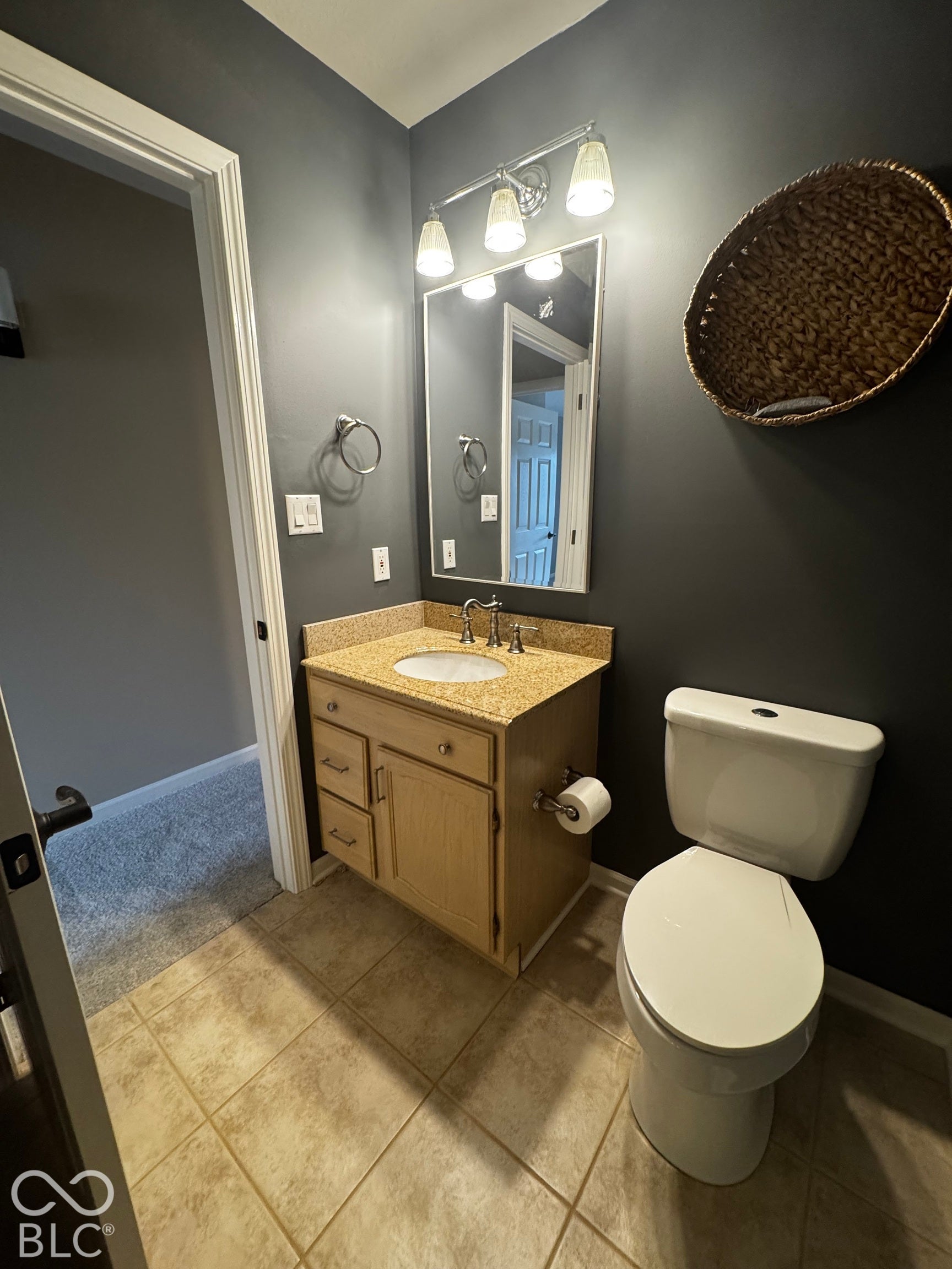 Vanity with a granite countertop and an integrated sink, framed mirror, and a three-light fixture
