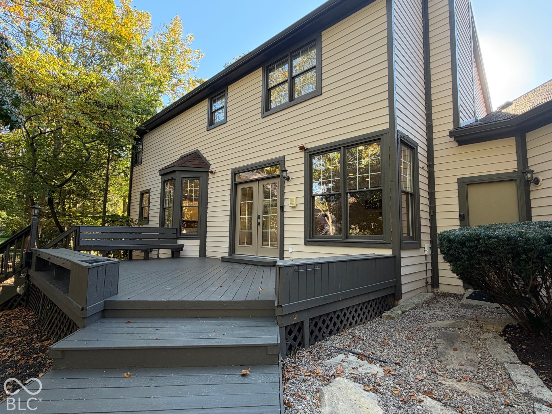 Exterior siding with dark trim accents, multi-level deck, bay window, and double French doors