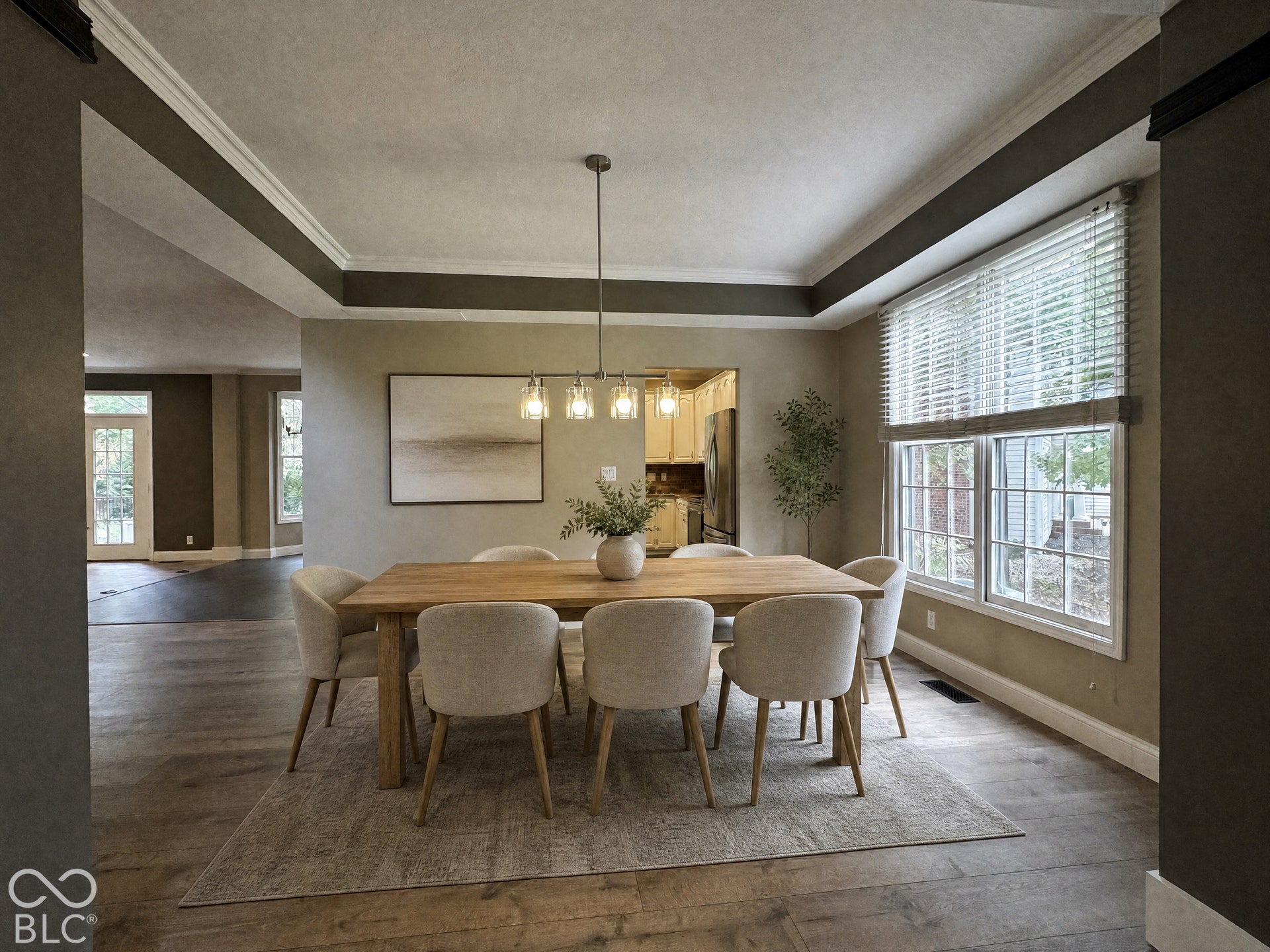 Virtually Altered - Tray ceiling with crown molding, wood-finish flooring, large window with blinds, and a built-in light fixture