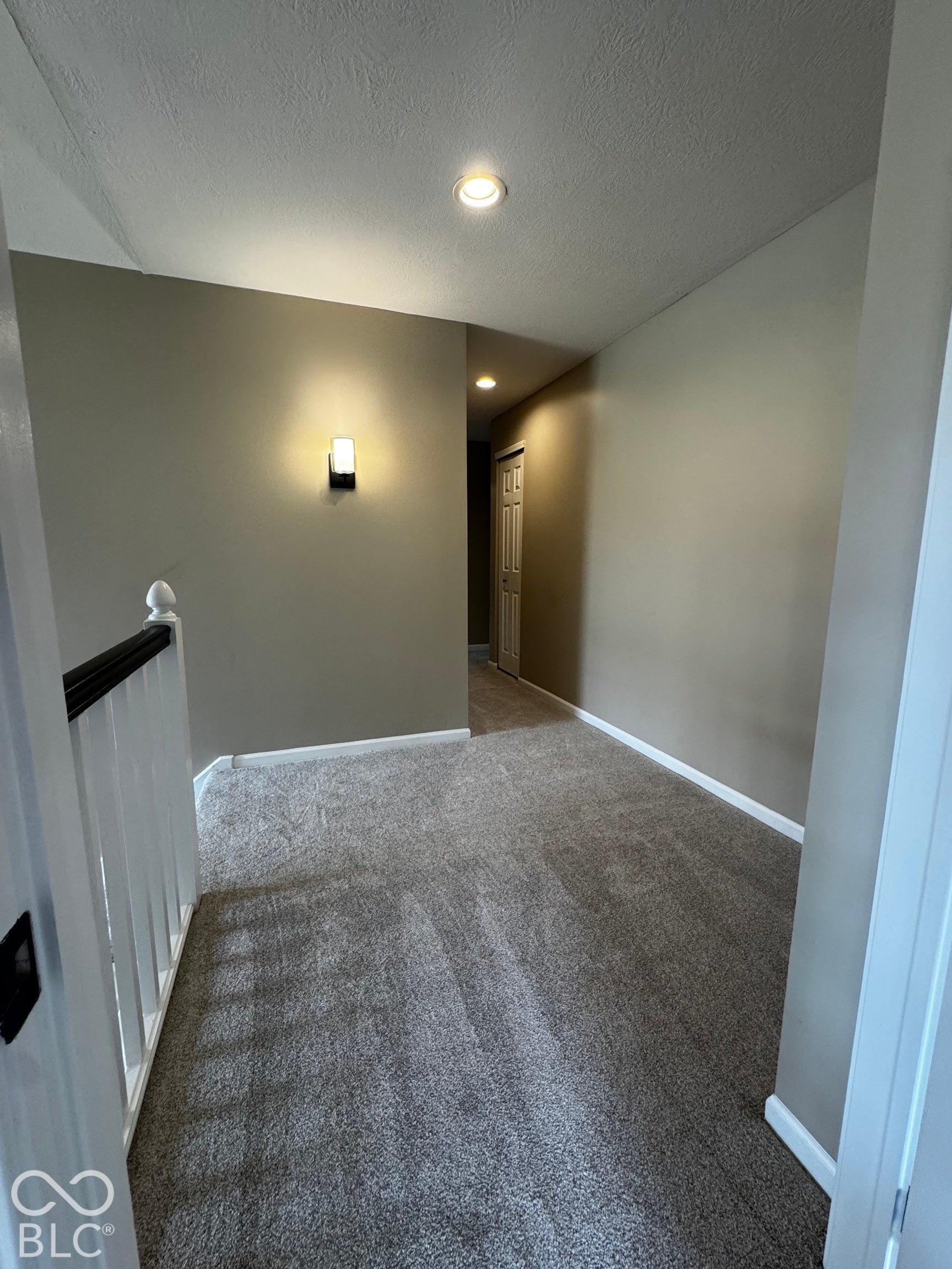 Recessed ceiling lighting, wall-mounted sconce, light gray wall paint, white trim, and gray carpeted flooring