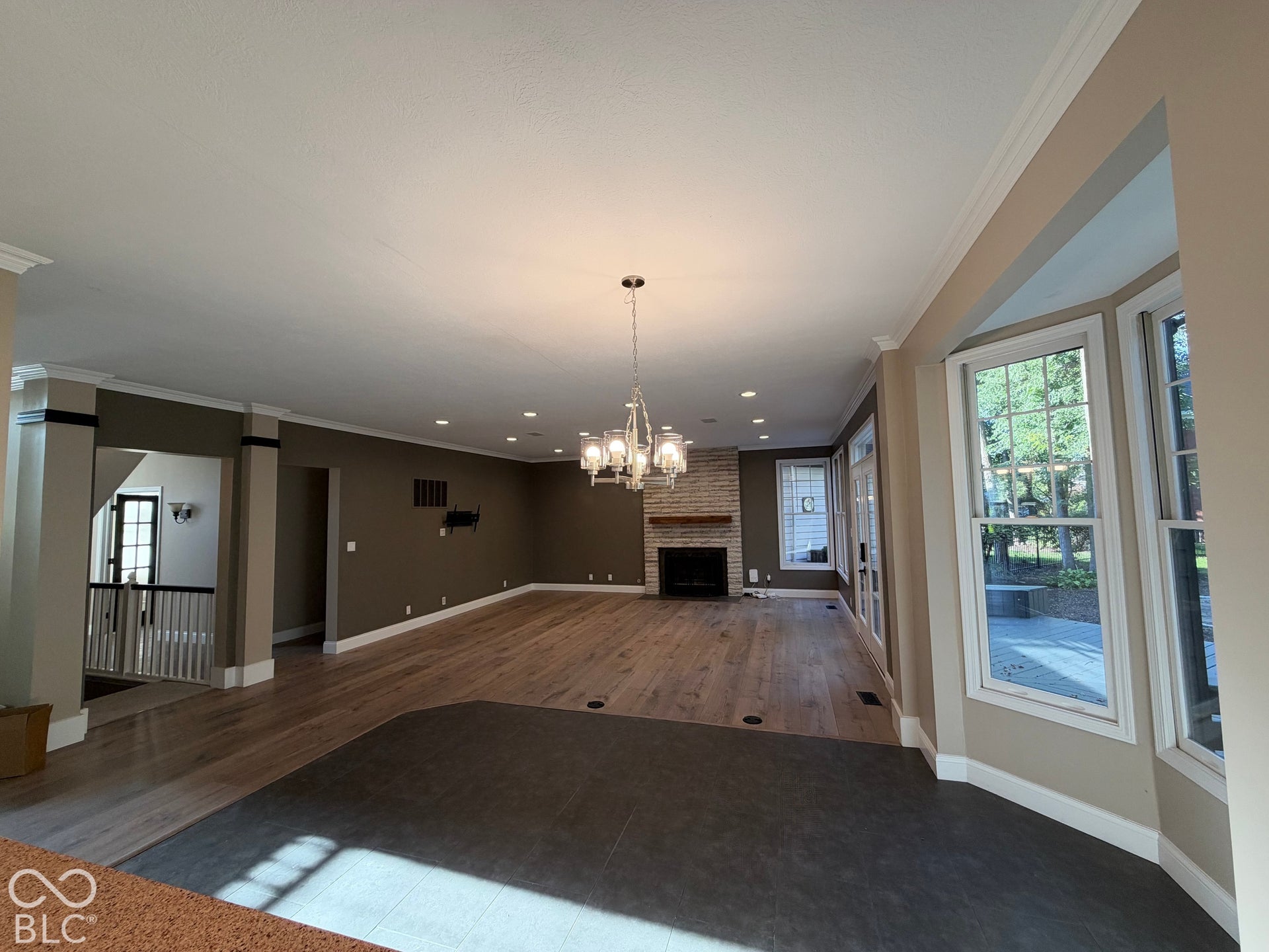 Spacious living area featuring wood-finish flooring, a brick fireplace with a wood mantle, a bay window, and recessed lighting