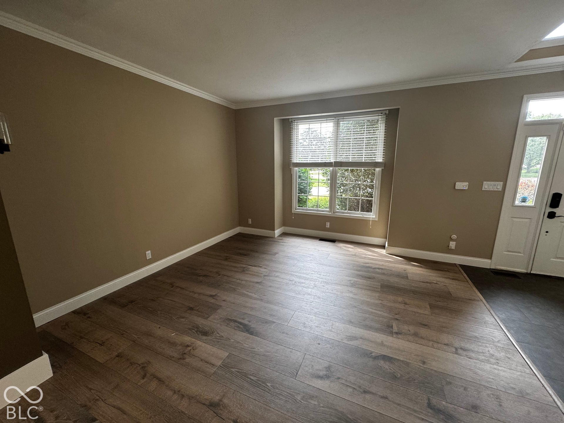Wood-finish flooring throughout, white trim, and a window with horizontal blinds