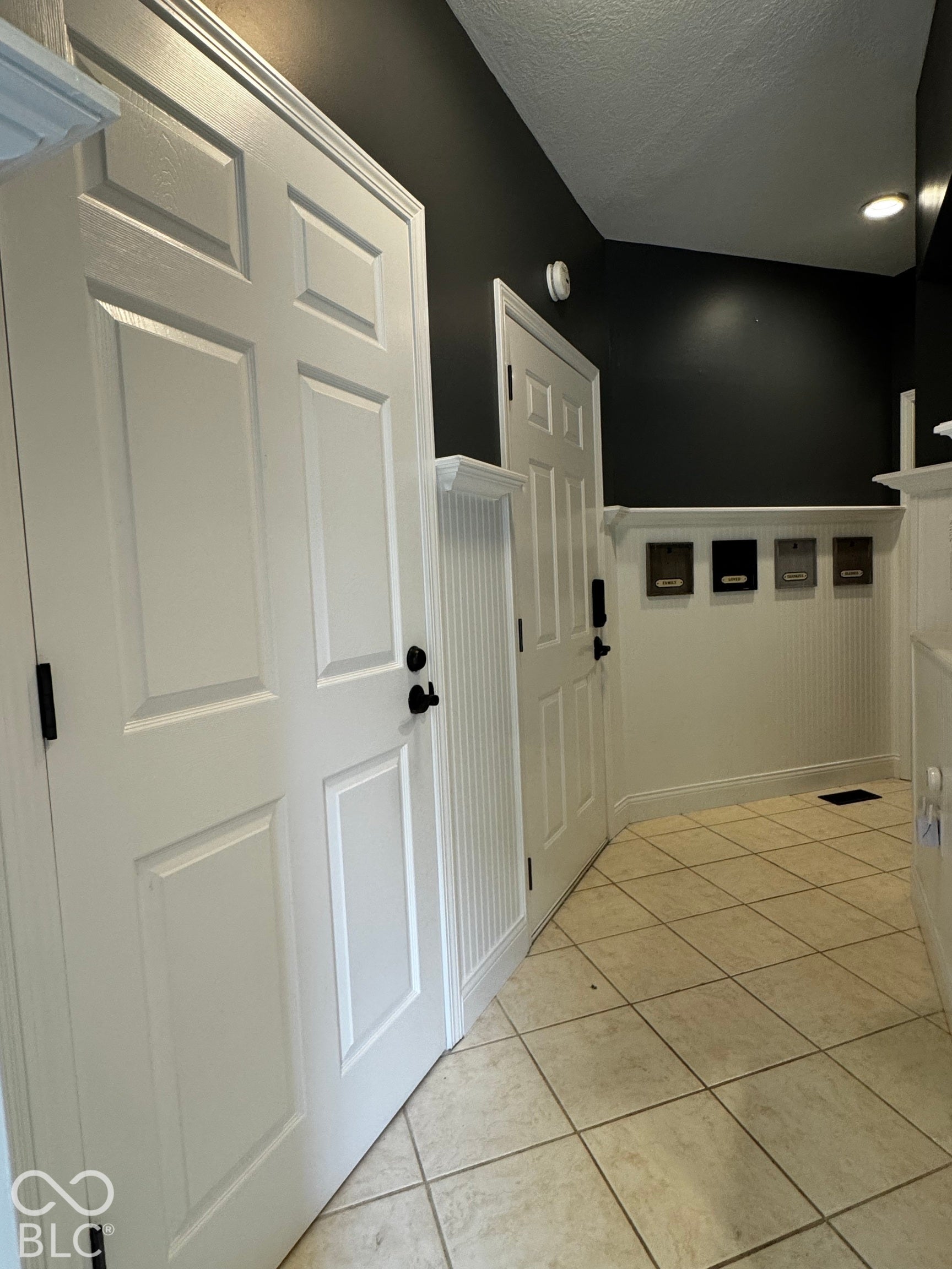 Recessed lighting illuminates the space, featuring white paneled doors and beadboard wainscoting