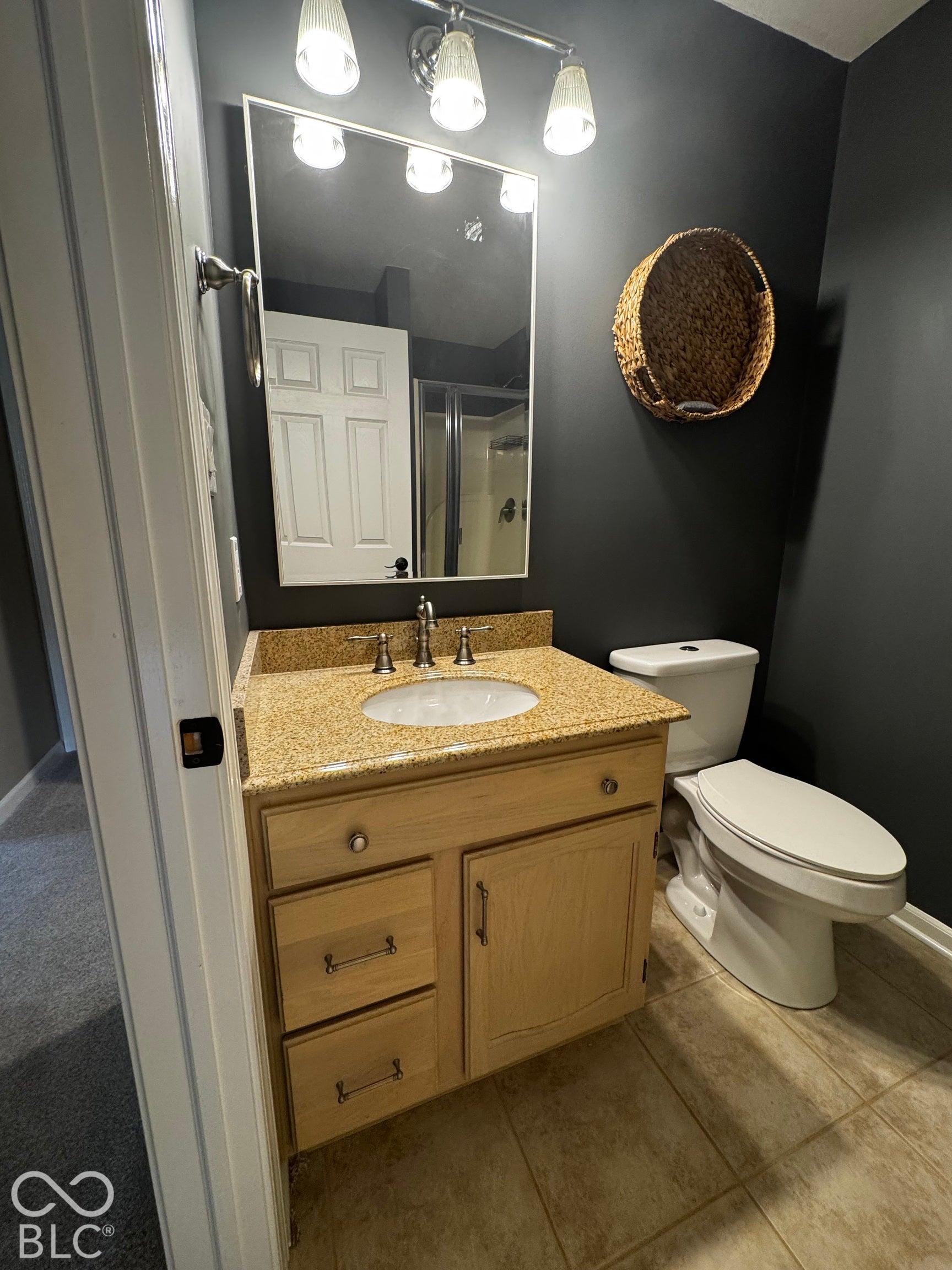 Bathroom featuring a light wood-finish vanity with a granite countertop, undermount sink, and brushed nickel fixtures