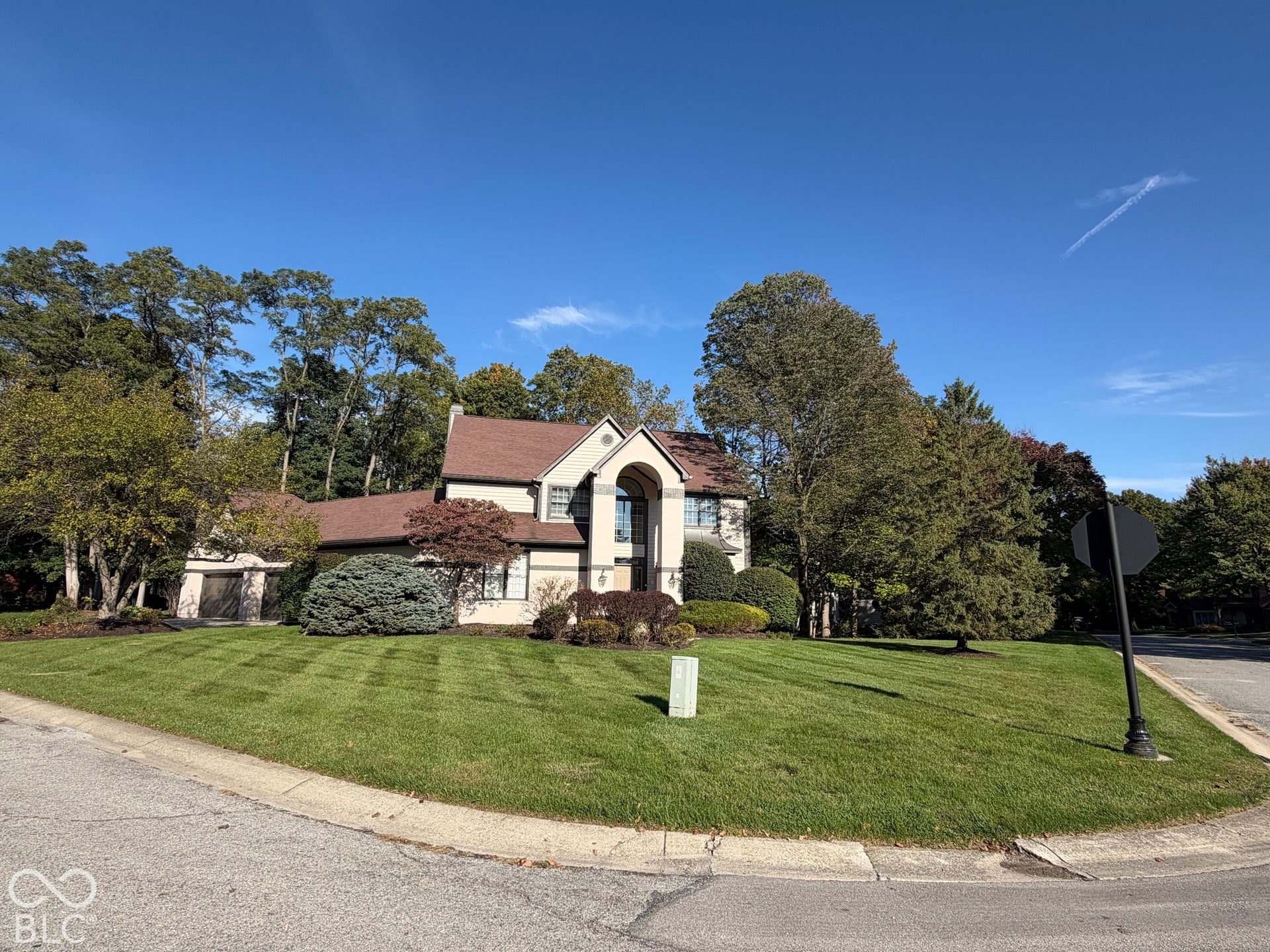 Traditional-style residence with a two-car garage, mature landscaping, and a manicured lawn