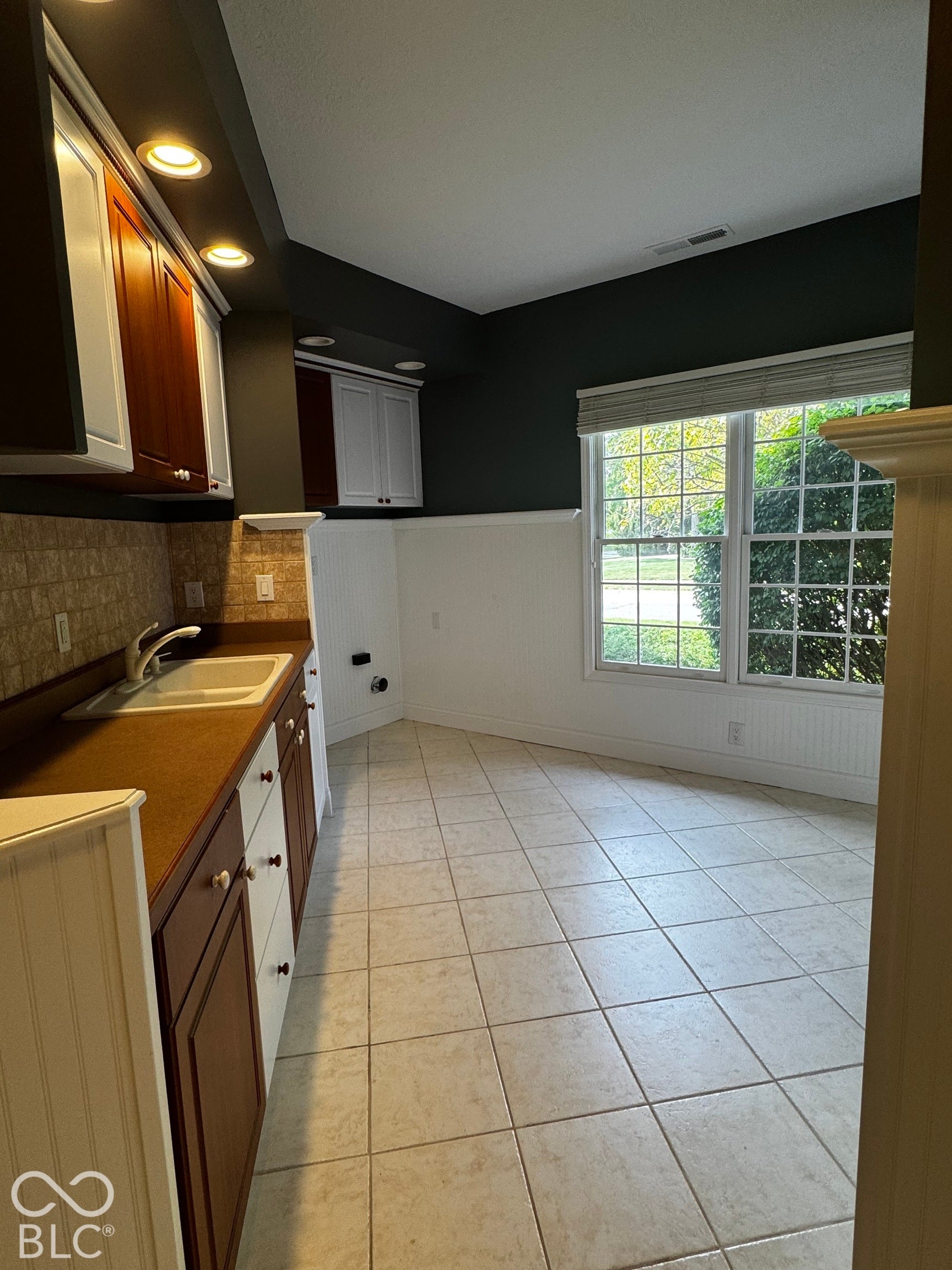 Kitchenette featuring recessed lighting, a built-in sink, two-tone cabinetry, tiled flooring, and a large window
