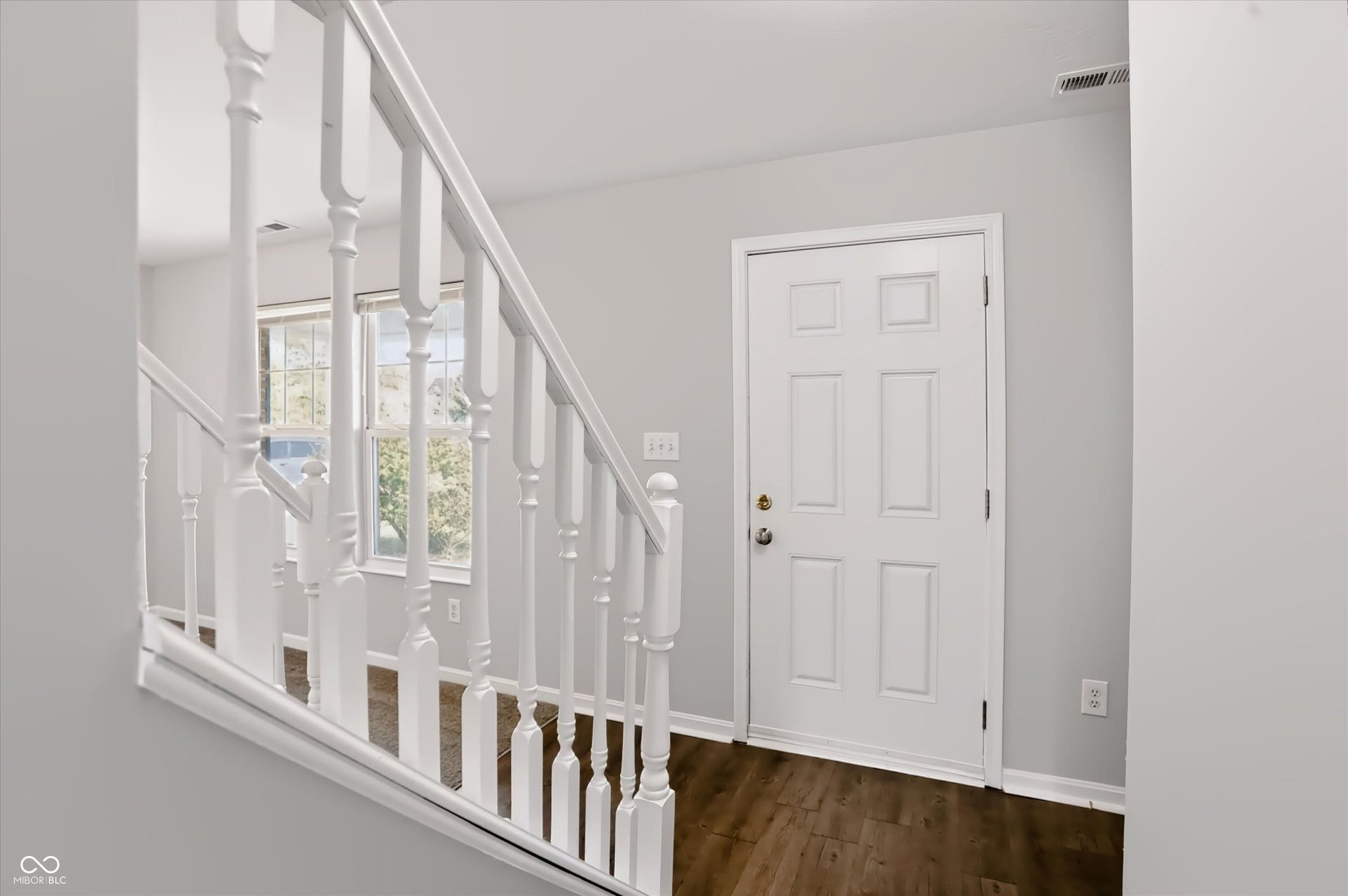 2536 Autumn Road, Indianapolis, IN 46229 Entryway featuring a paneled door, wood-finish flooring, and a white baluster staircase