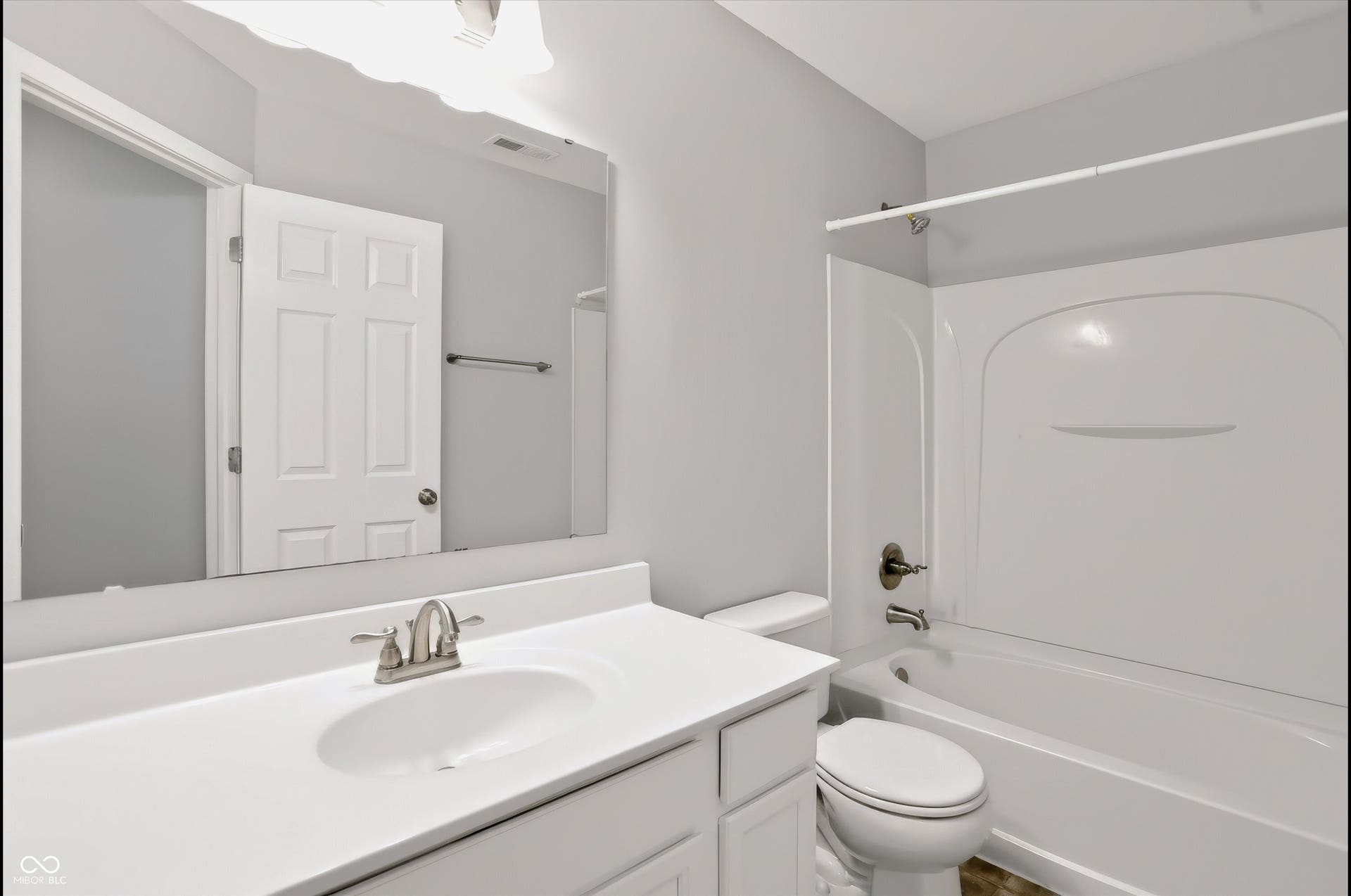 2536 Autumn Road, Indianapolis, IN 46229 Bathroom featuring a vanity with an integrated sink, brushed nickel faucet, a large mirror, a white toilet, and a bathtub with a shower