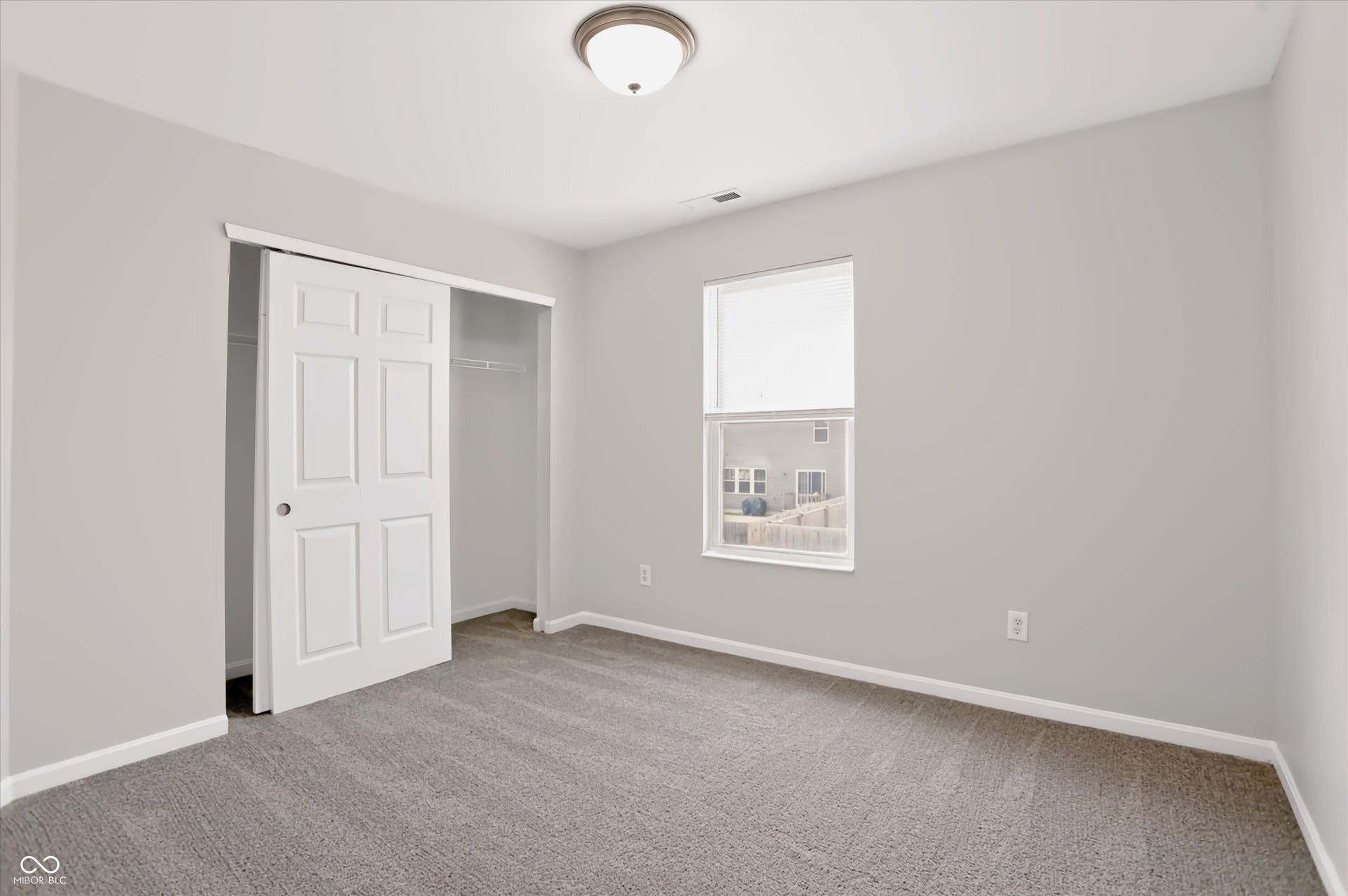 2536 Autumn Road, Indianapolis, IN 46229 Neutral wall color, carpet flooring, window with blind, six-panel sliding closet door, and flush-mount ceiling light