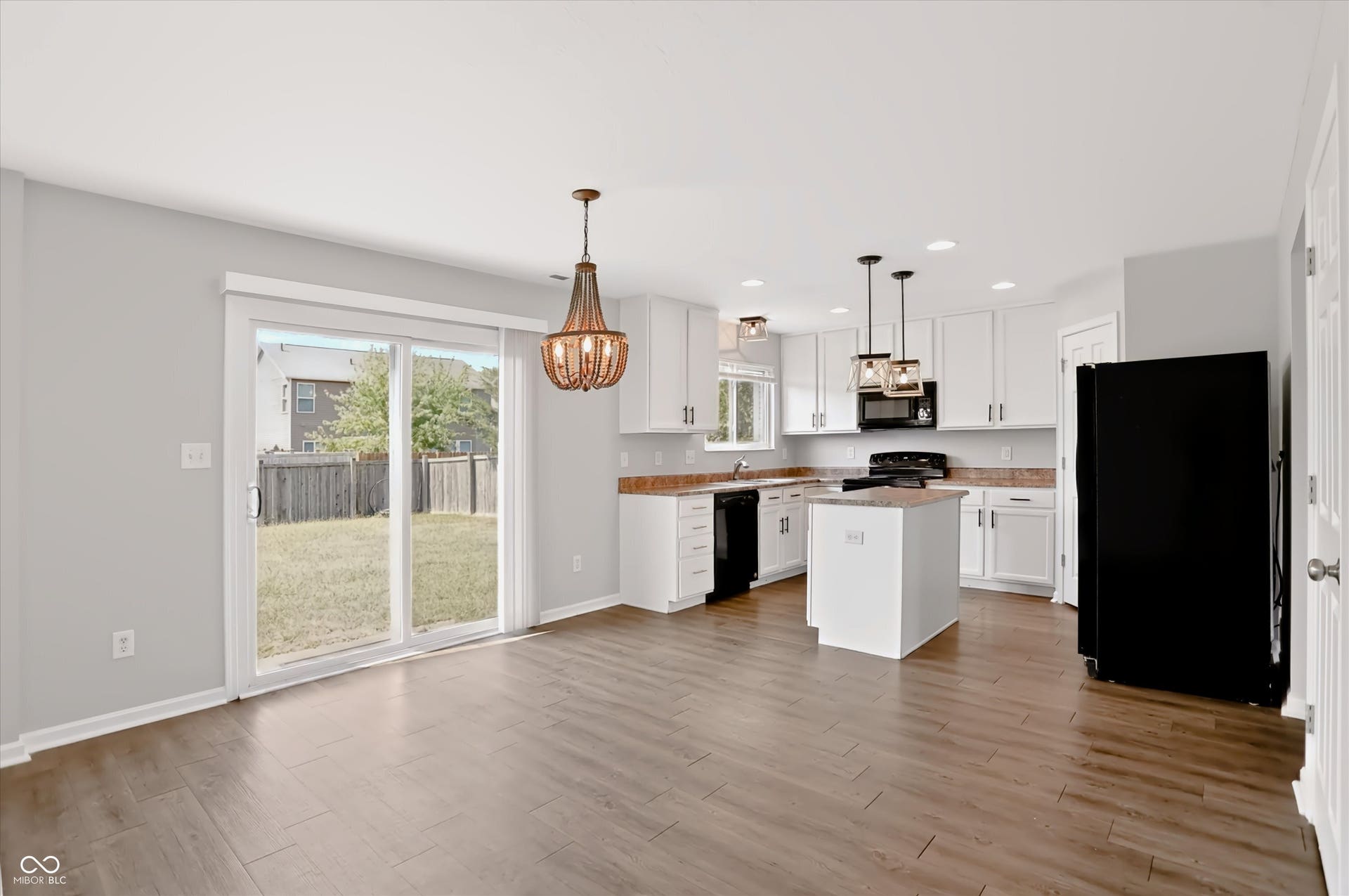 2536 Autumn Road, Indianapolis, IN 46229 Open-concept kitchen with white cabinetry and an island, wood-finish flooring, and sliding glass doors to the backyard