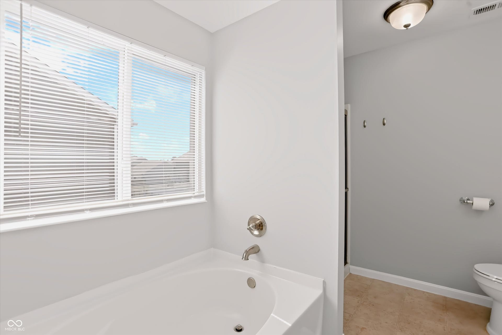 2536 Autumn Road, Indianapolis, IN 46229 White bathtub with brushed nickel fixtures, a large window, and light-toned wall paint
