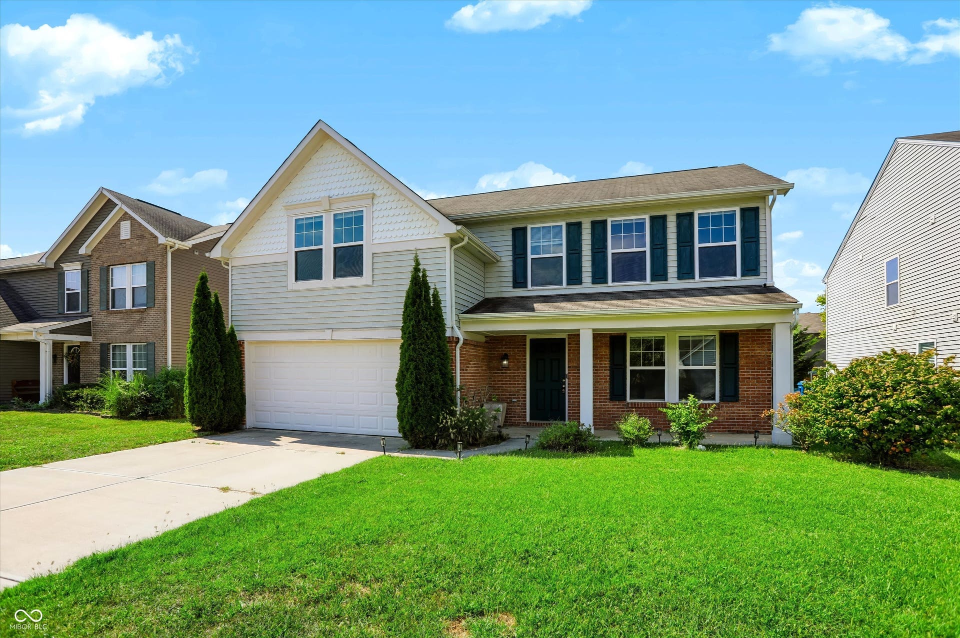 2536 Autumn Road, Indianapolis, IN 46229 Two-story home with a brick and siding exterior, featuring a covered front porch, an attached garage, and a concrete driveway