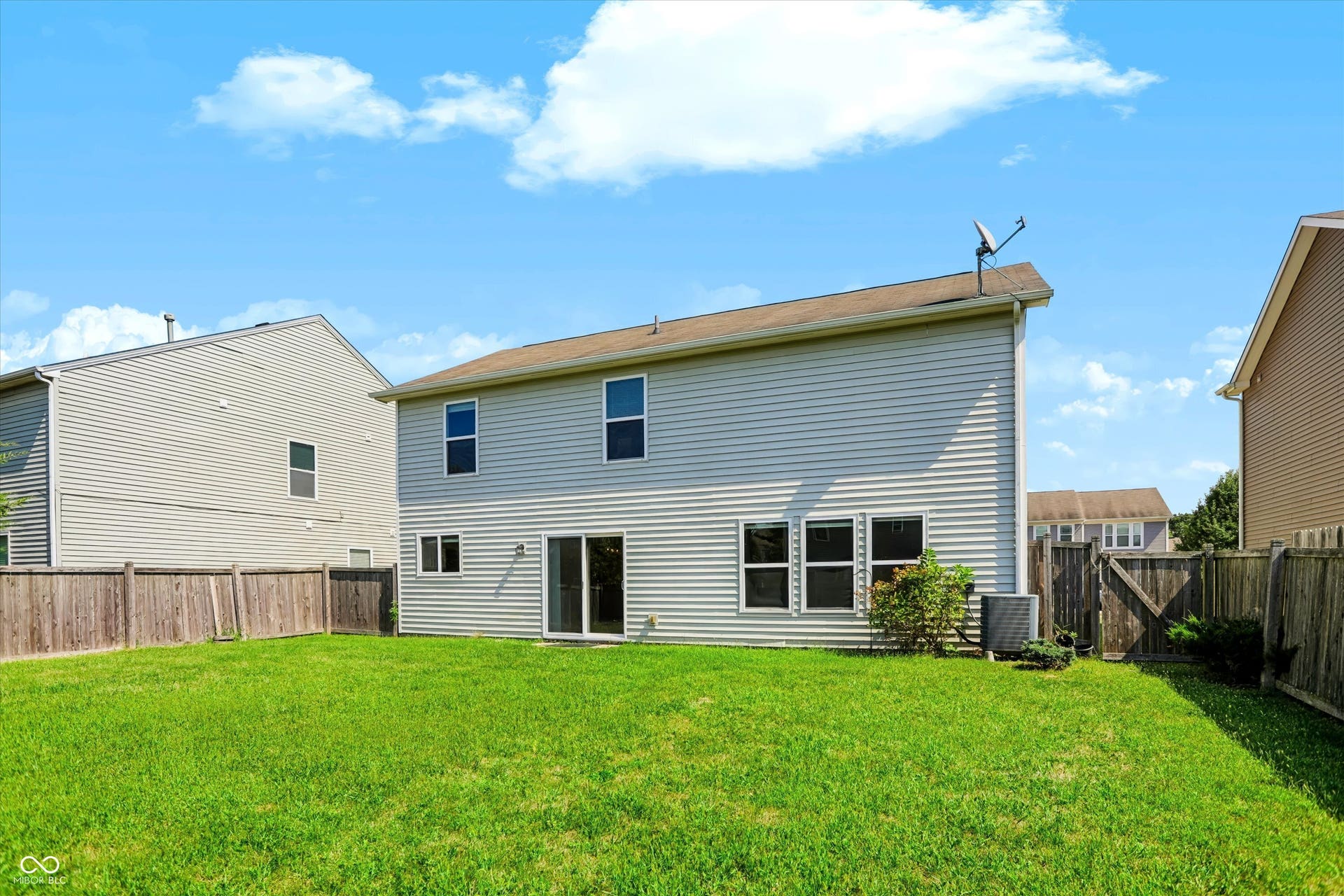 2536 Autumn Road, Indianapolis, IN 46229 Expansive green lawn with a wooden perimeter fence, two-story exterior siding, and a sliding glass door