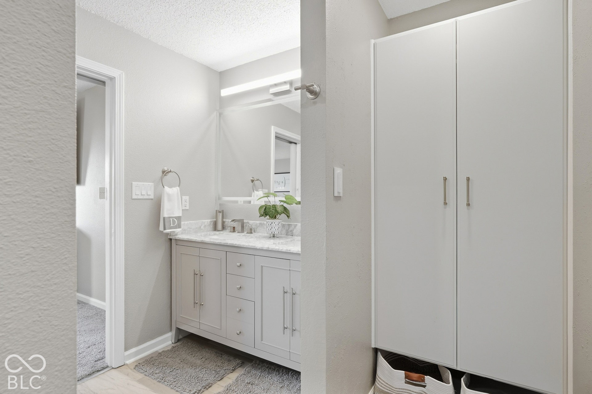 Built-in storage cabinet, vanity with stone countertop, undermount sink, and wall-mounted lighting