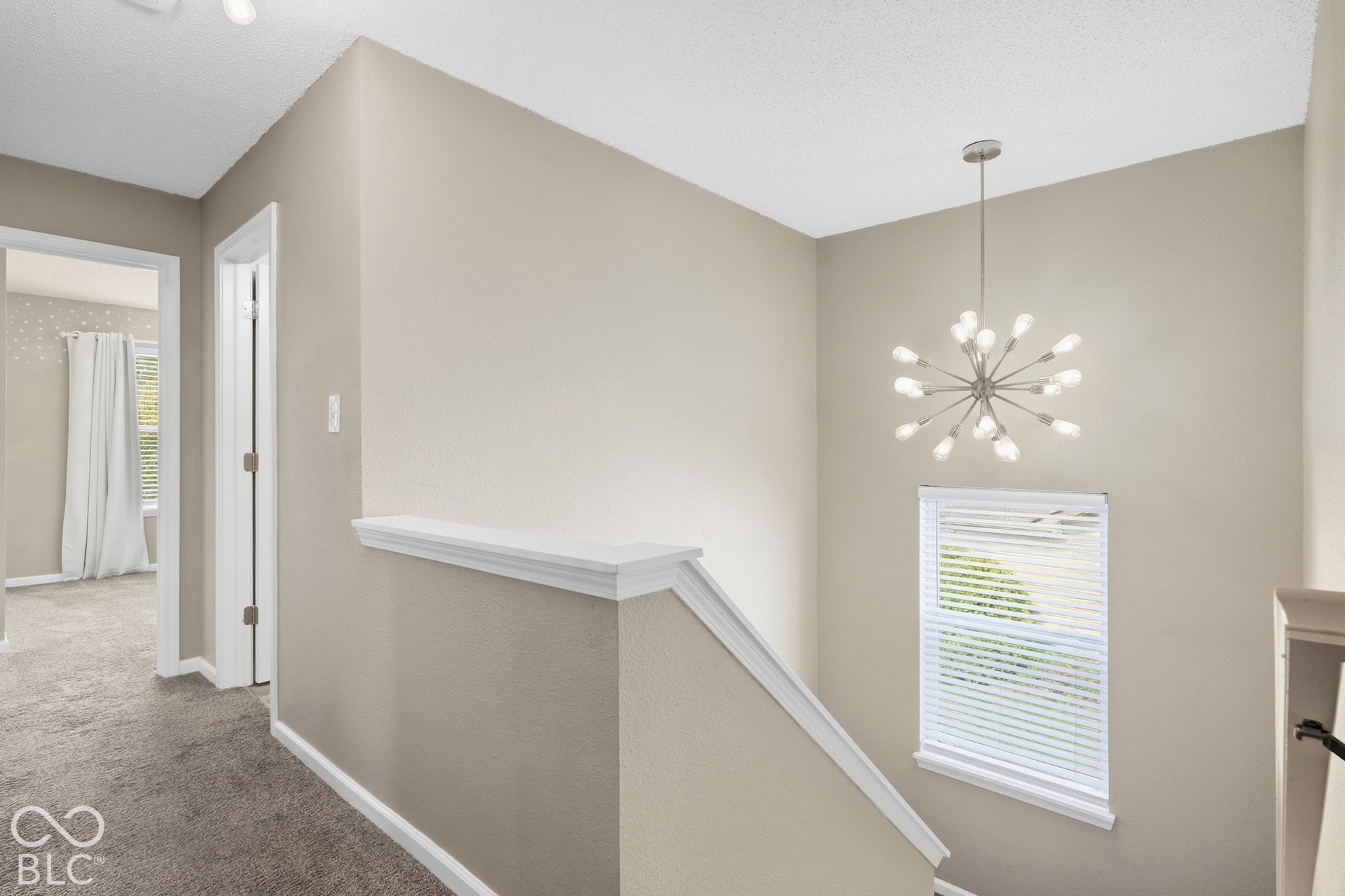 Upper level landing with neutral wall paint, gray carpet, white trim, and a contemporary sputnik chandelier