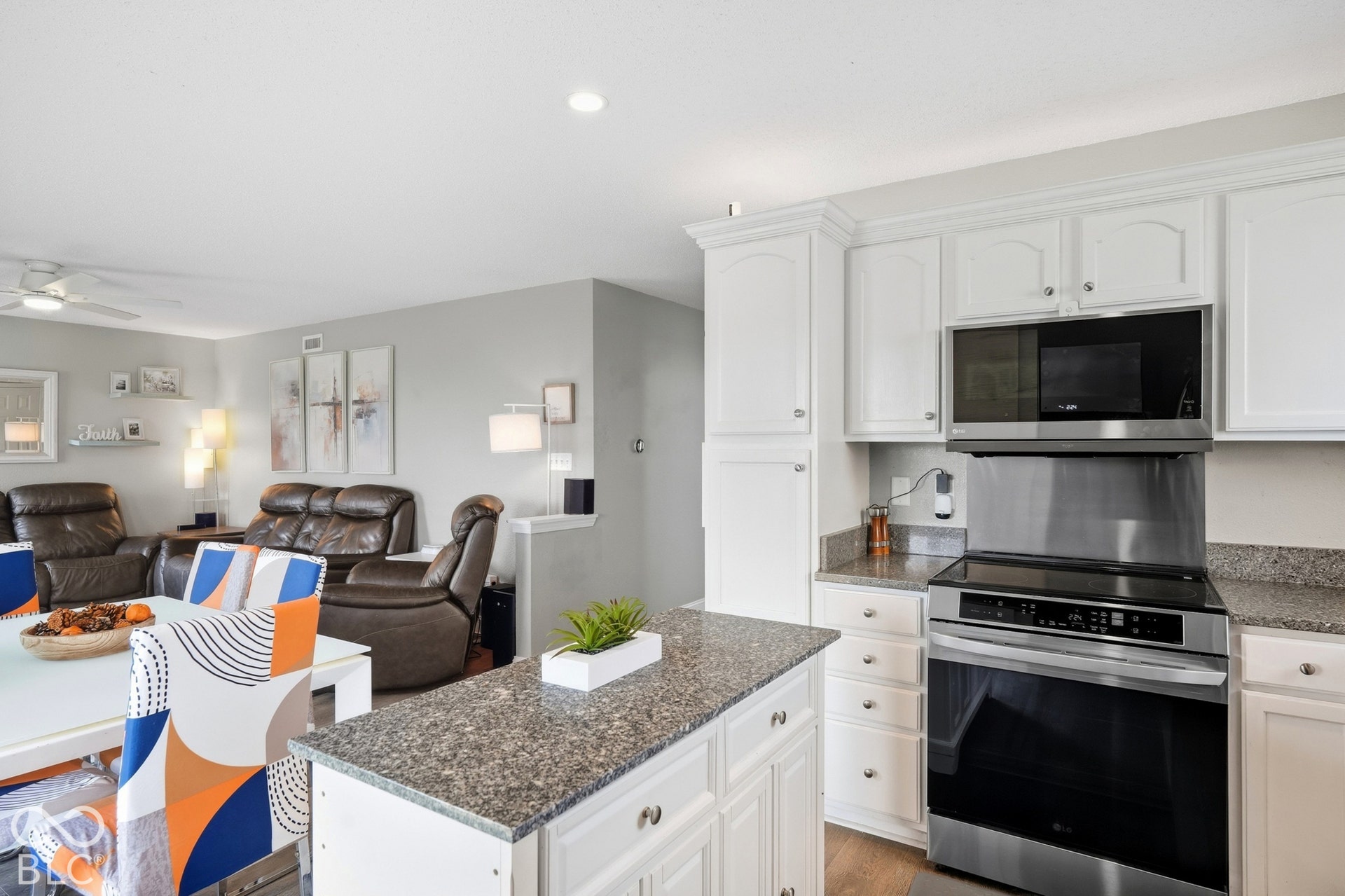 White cabinetry, stainless steel microwave, stainless steel range, and stone countertops